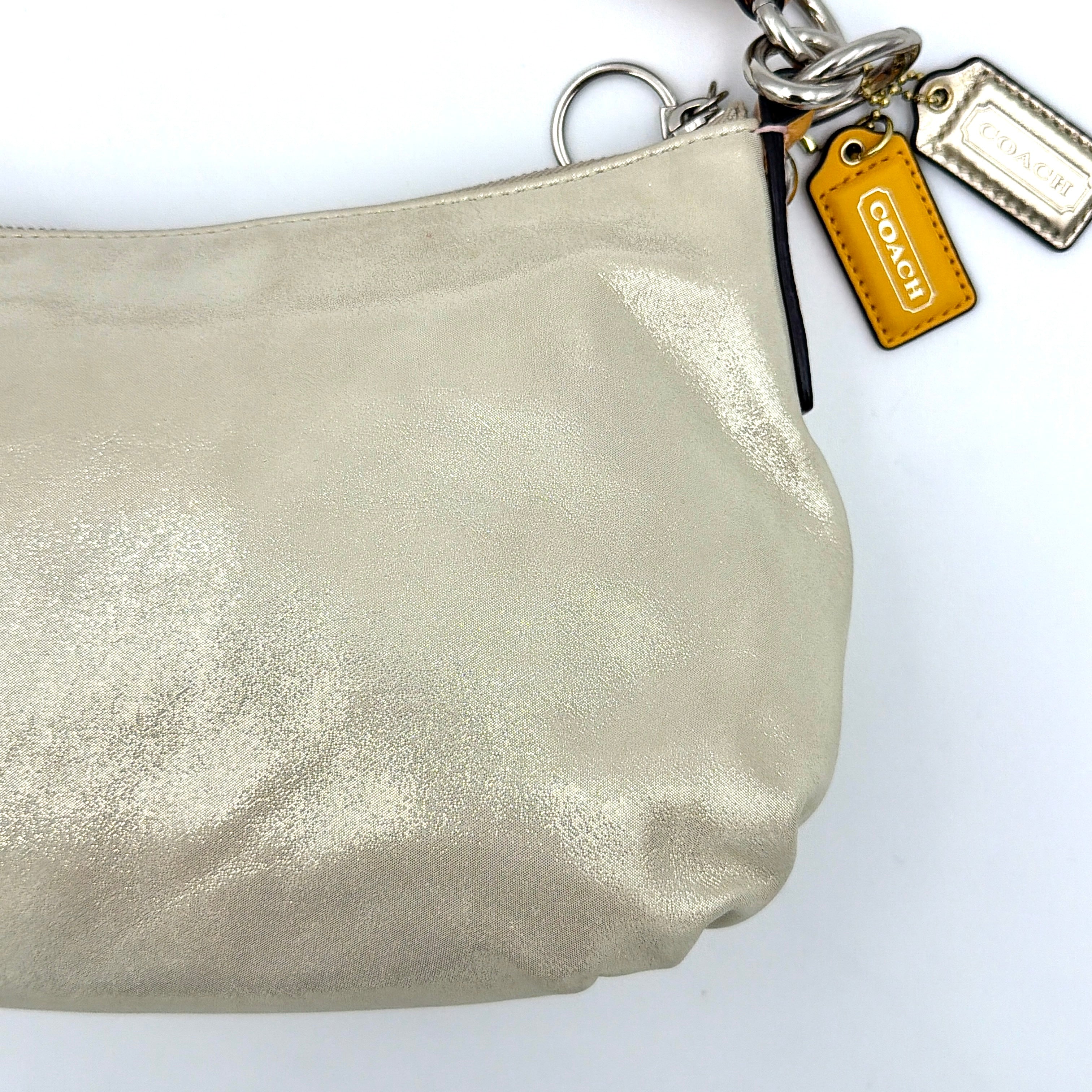 Coach Poppy Sparkle Groovy bag in cream with tan trim, metallic plaque, and detachable shoulder strap displayed alongside.