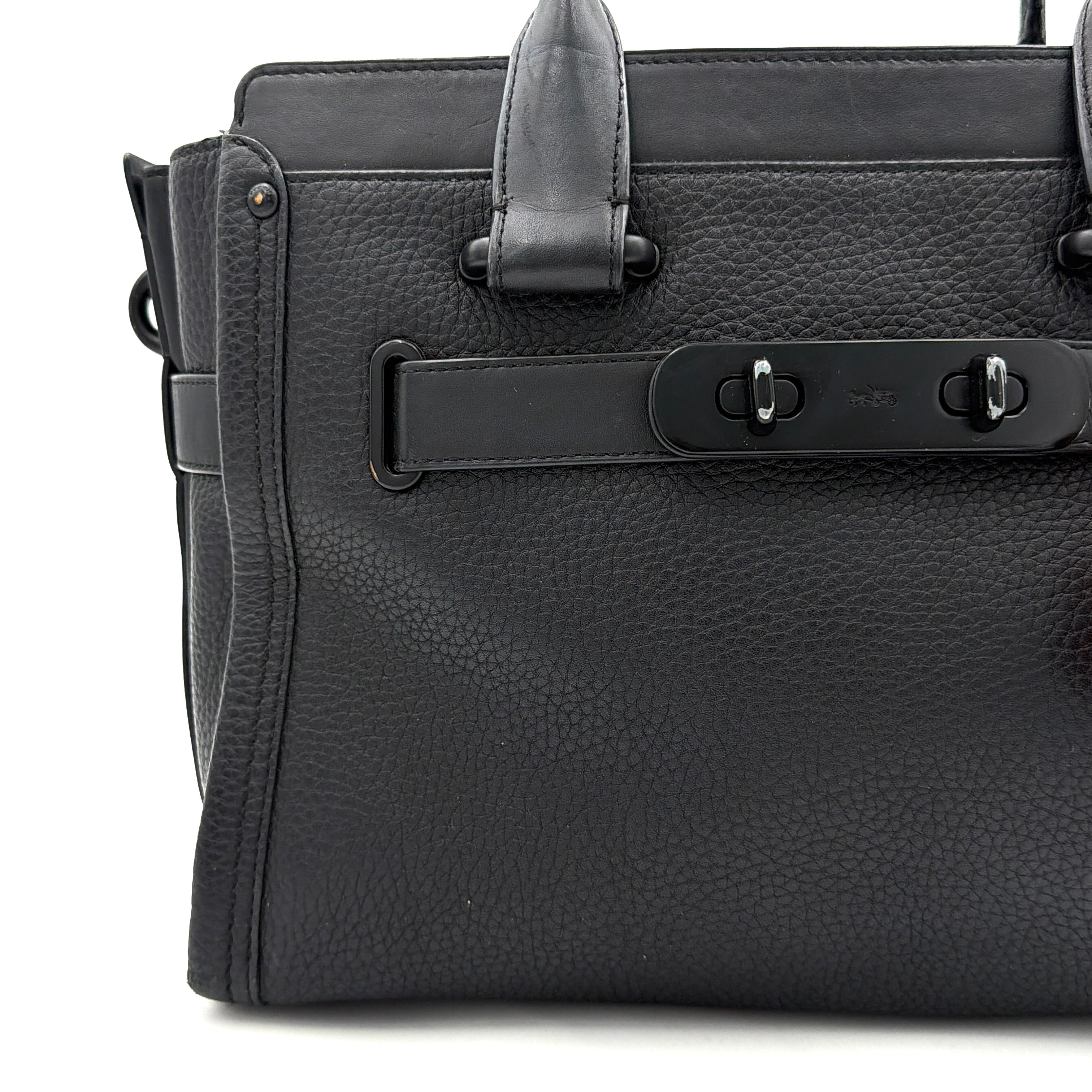Coach Swagger Carryall handbag in black pebbled leather with matte black hardware and a vibrant orange butterfly charm.
