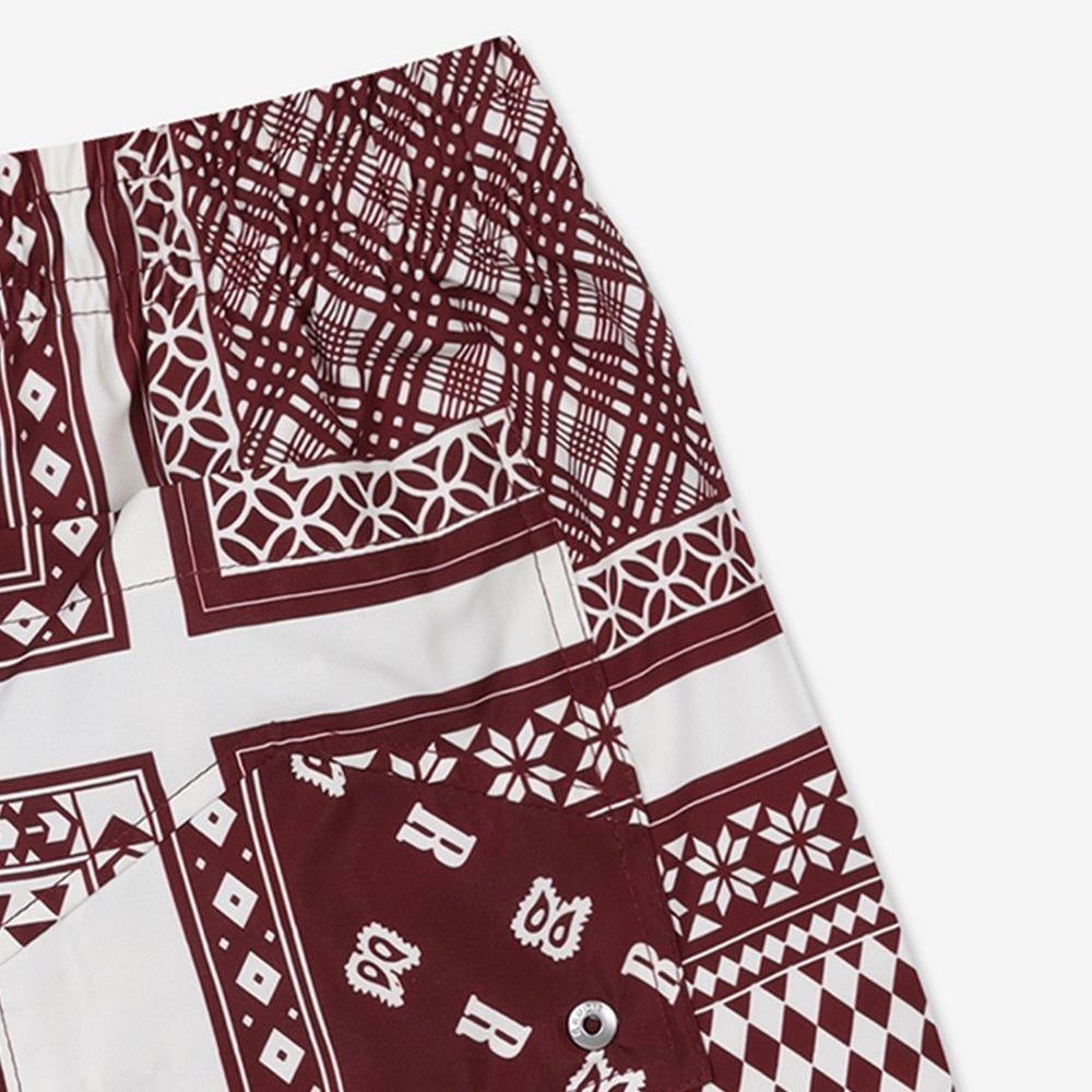 Rhude maroon and white swim shorts with a card print pattern and yellow drawstring, presented flat.