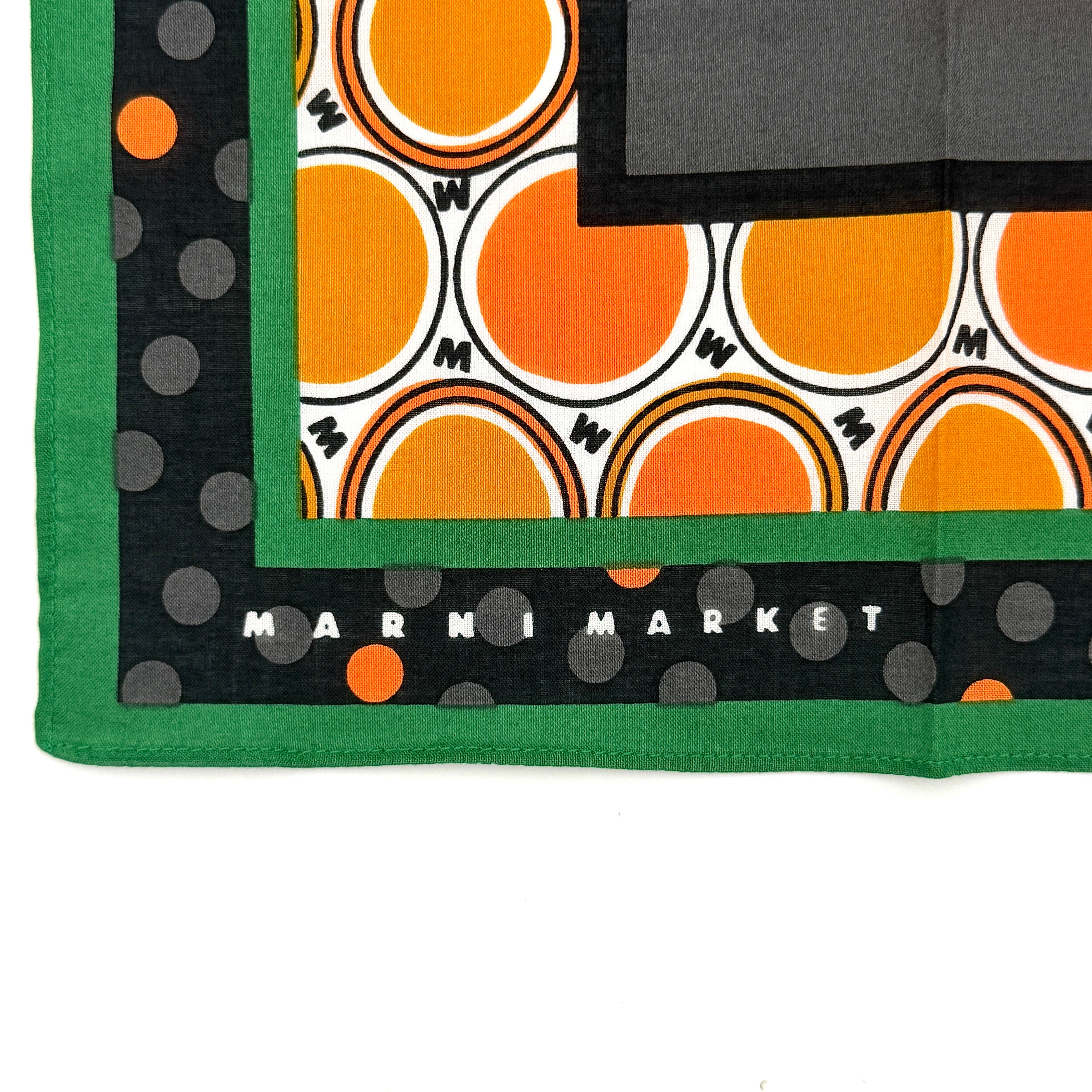 A Marni Market square scarf in orange polka dots and geometric borders with green edges, neatly laid out to show its graphic pattern.