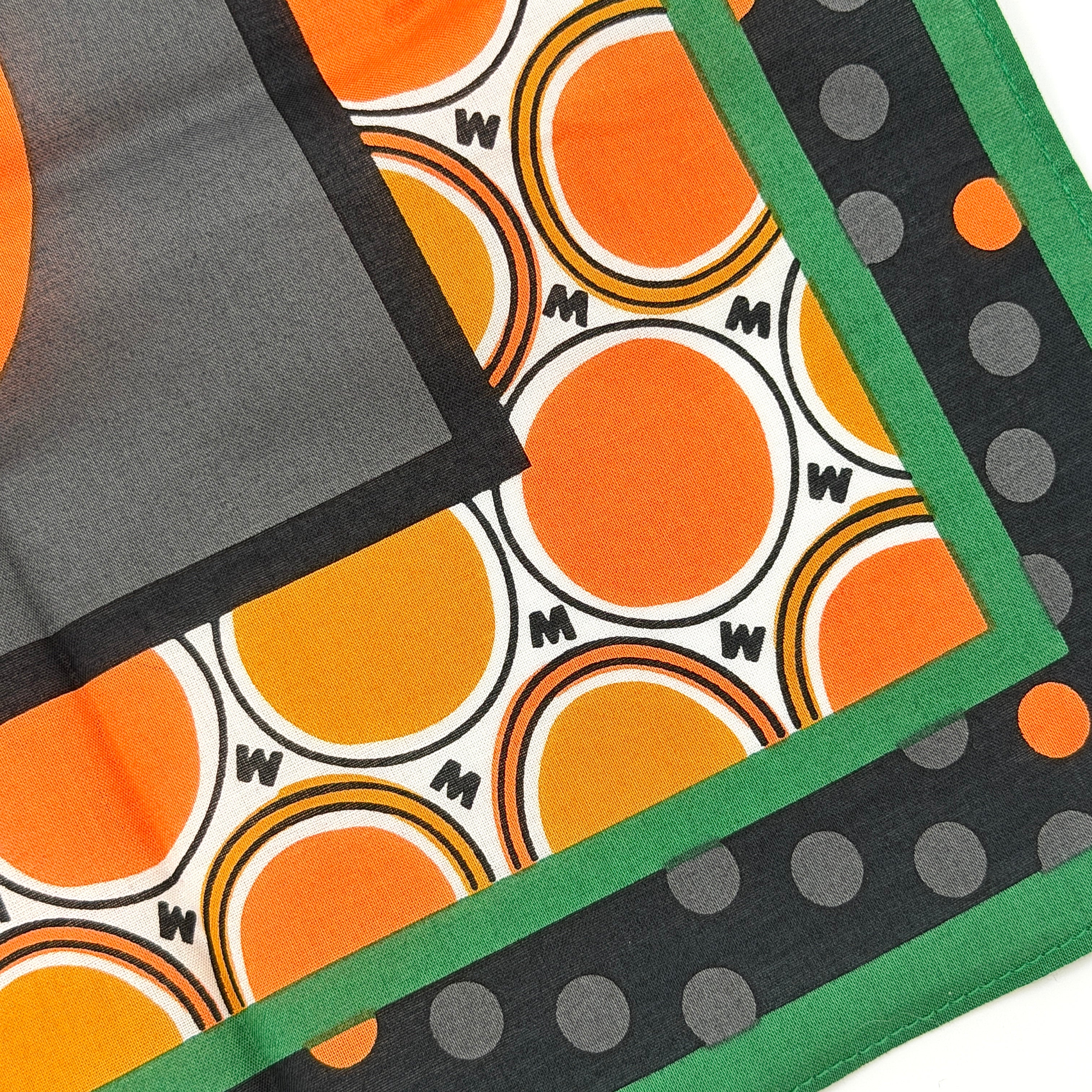 A Marni Market square scarf in orange polka dots and geometric borders with green edges, neatly laid out to show its graphic pattern.