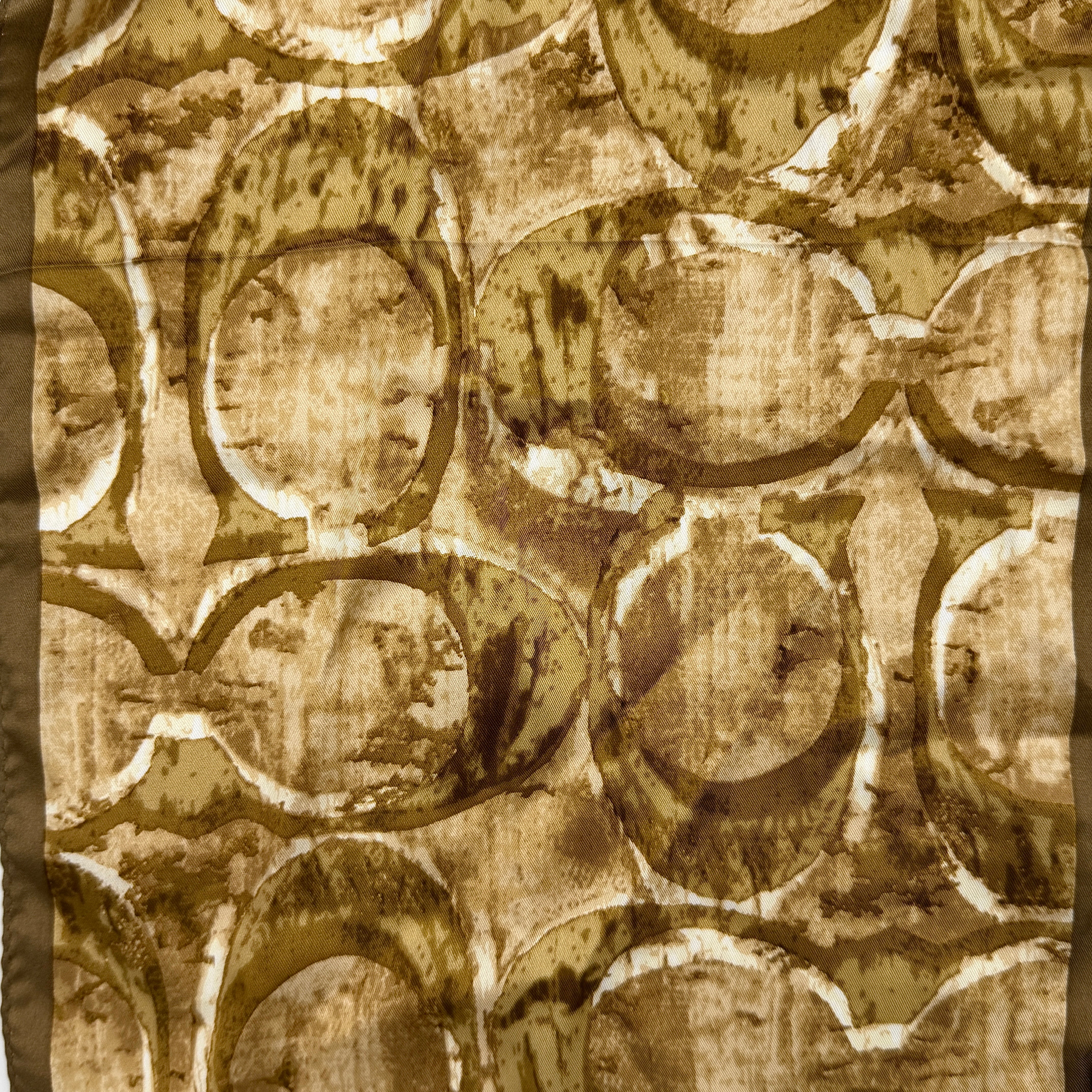 Coach silk scarf in rich brown tones, featuring an oversized signature monogram pattern and solid brown trim.
