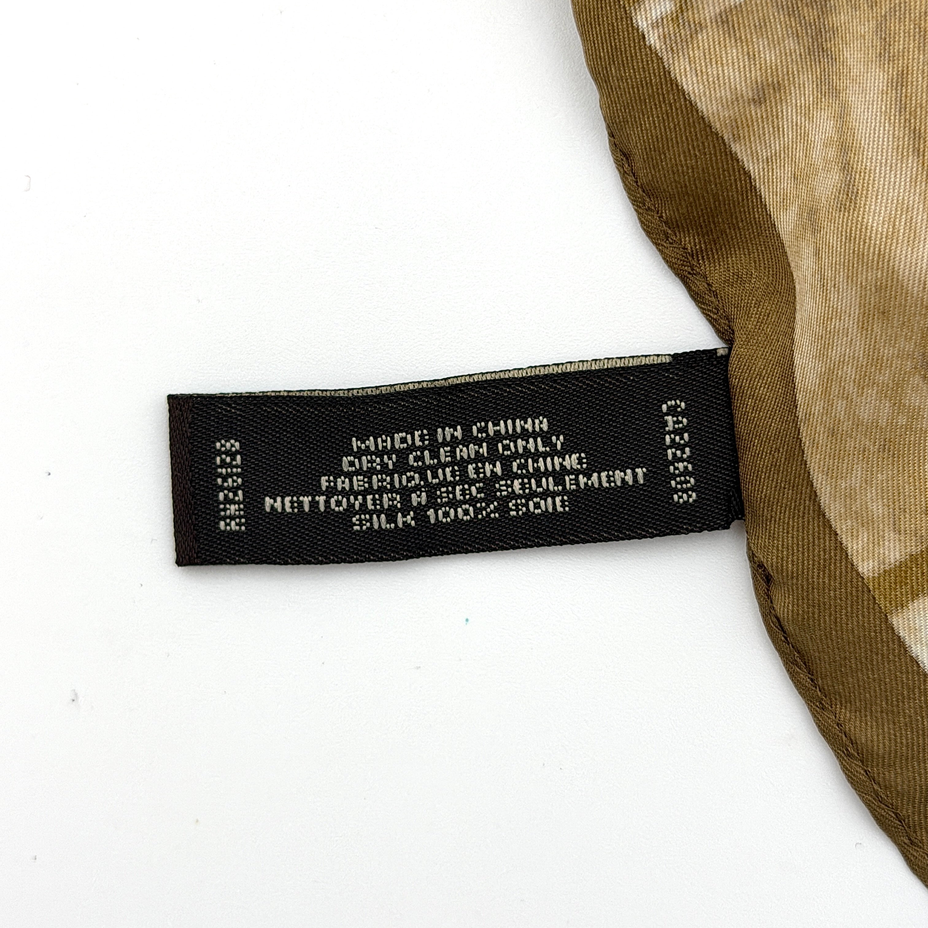 Coach silk scarf in rich brown tones, featuring an oversized signature monogram pattern and solid brown trim.