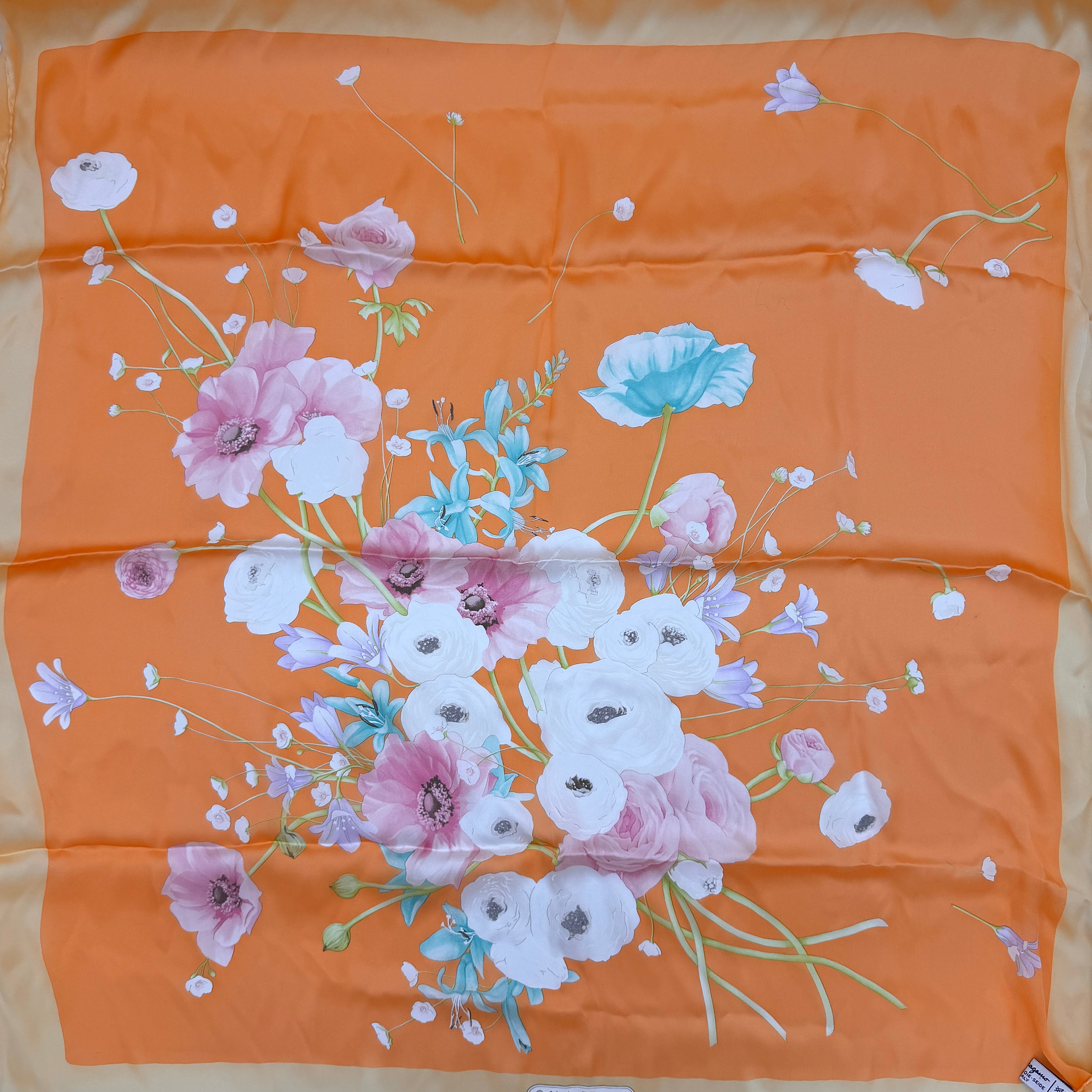 An orange Salvatore Ferragamo silk scarf with pastel floral print displayed in a gentle drape.
