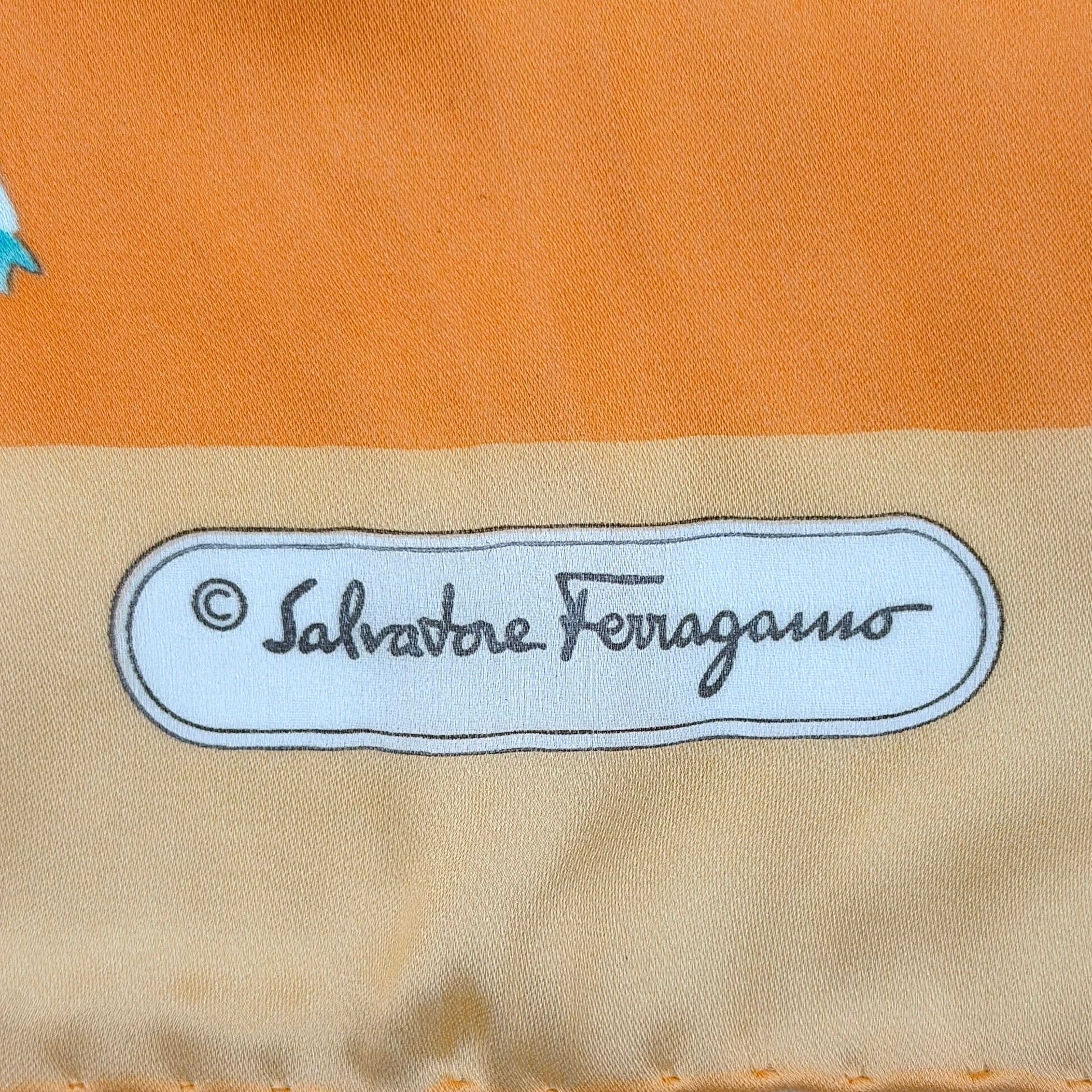 An orange Salvatore Ferragamo silk scarf with pastel floral print displayed in a gentle drape.