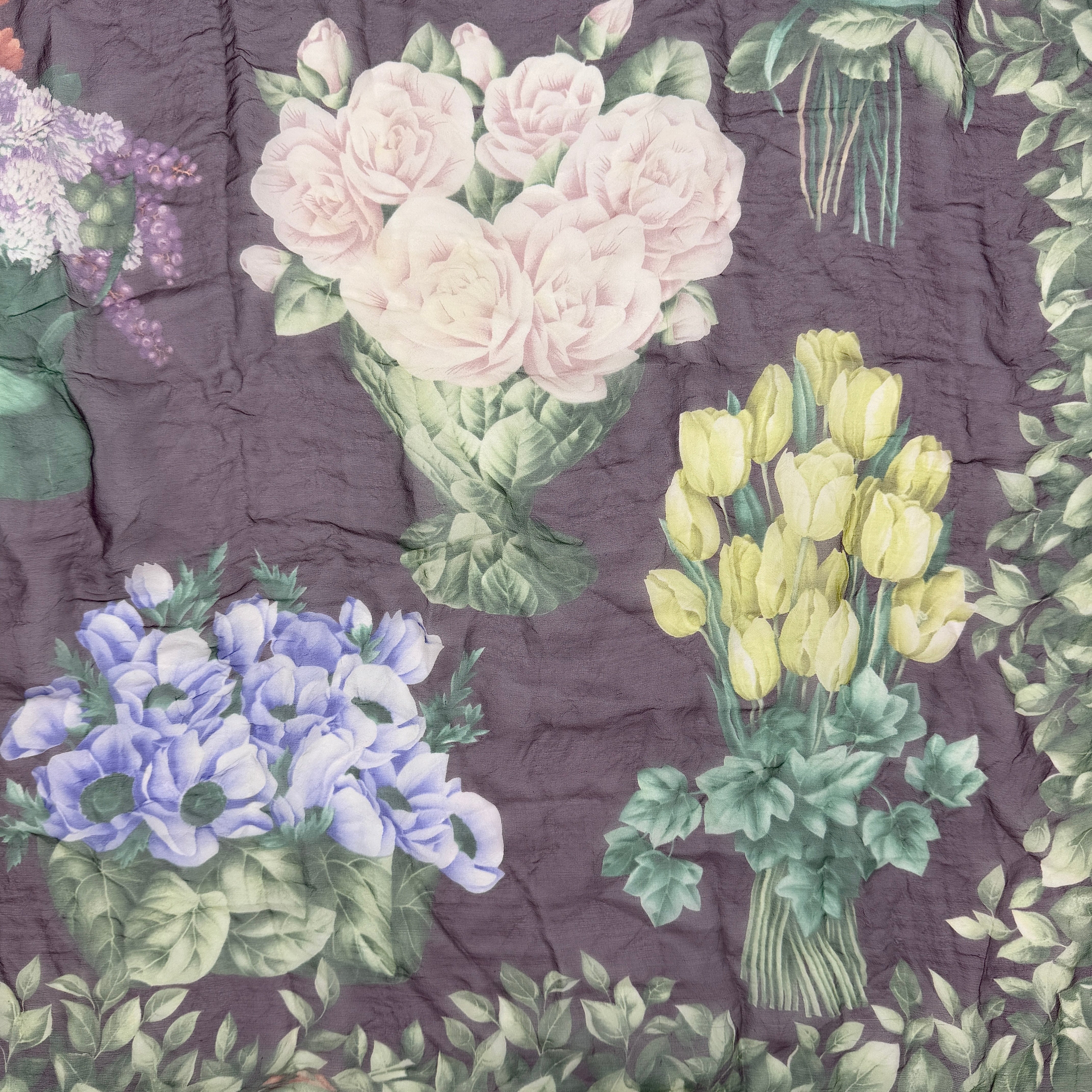 Gucci silk scarf adorned with artistic multicolour floral bouquets and leafy green border, elegantly draped to showcase its lightweight, sheer texture.