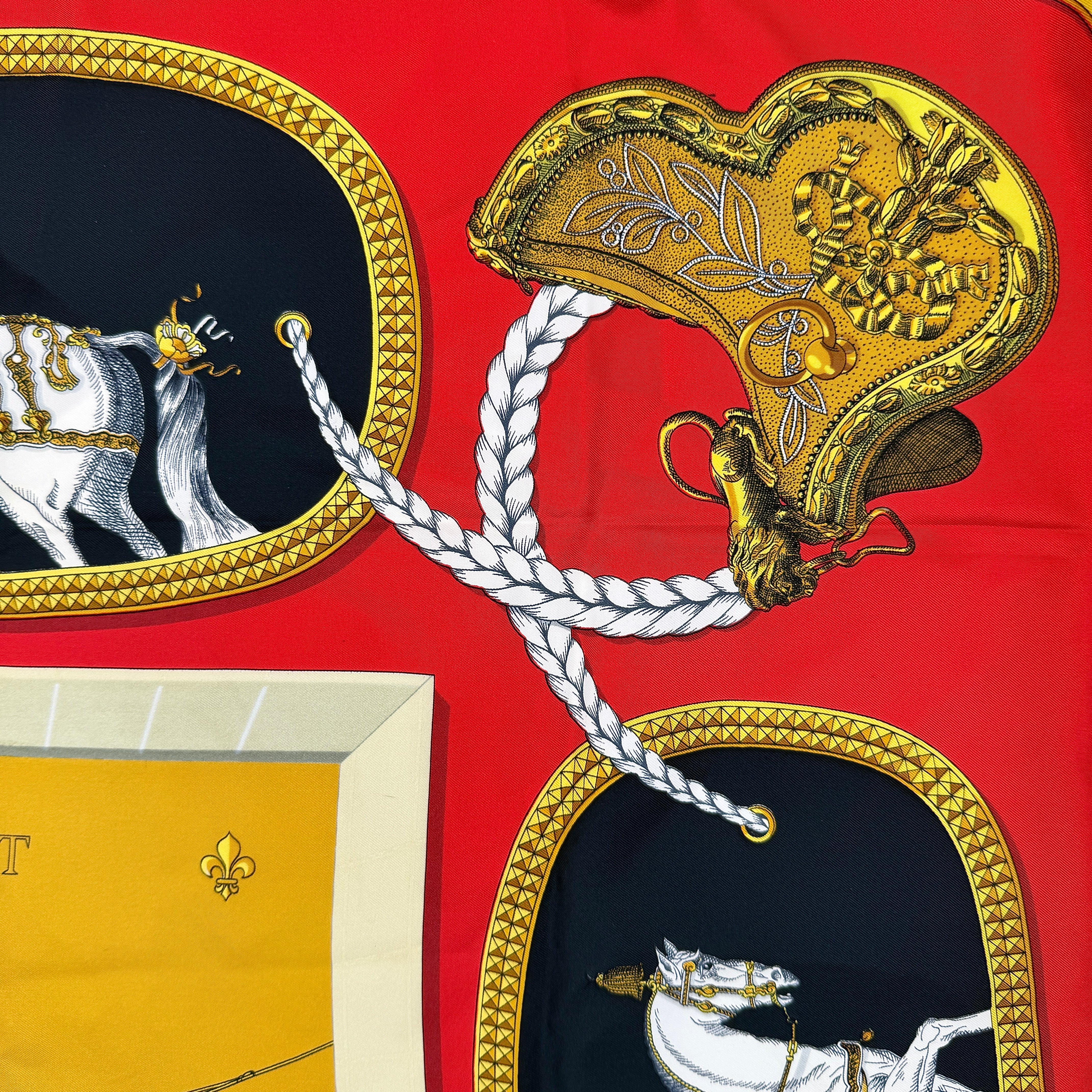 Hermès Grand Apparat silk scarf, featuring an ornate equestrian motif in rich red, gold, and black, elegantly folded to showcase its intricate print.