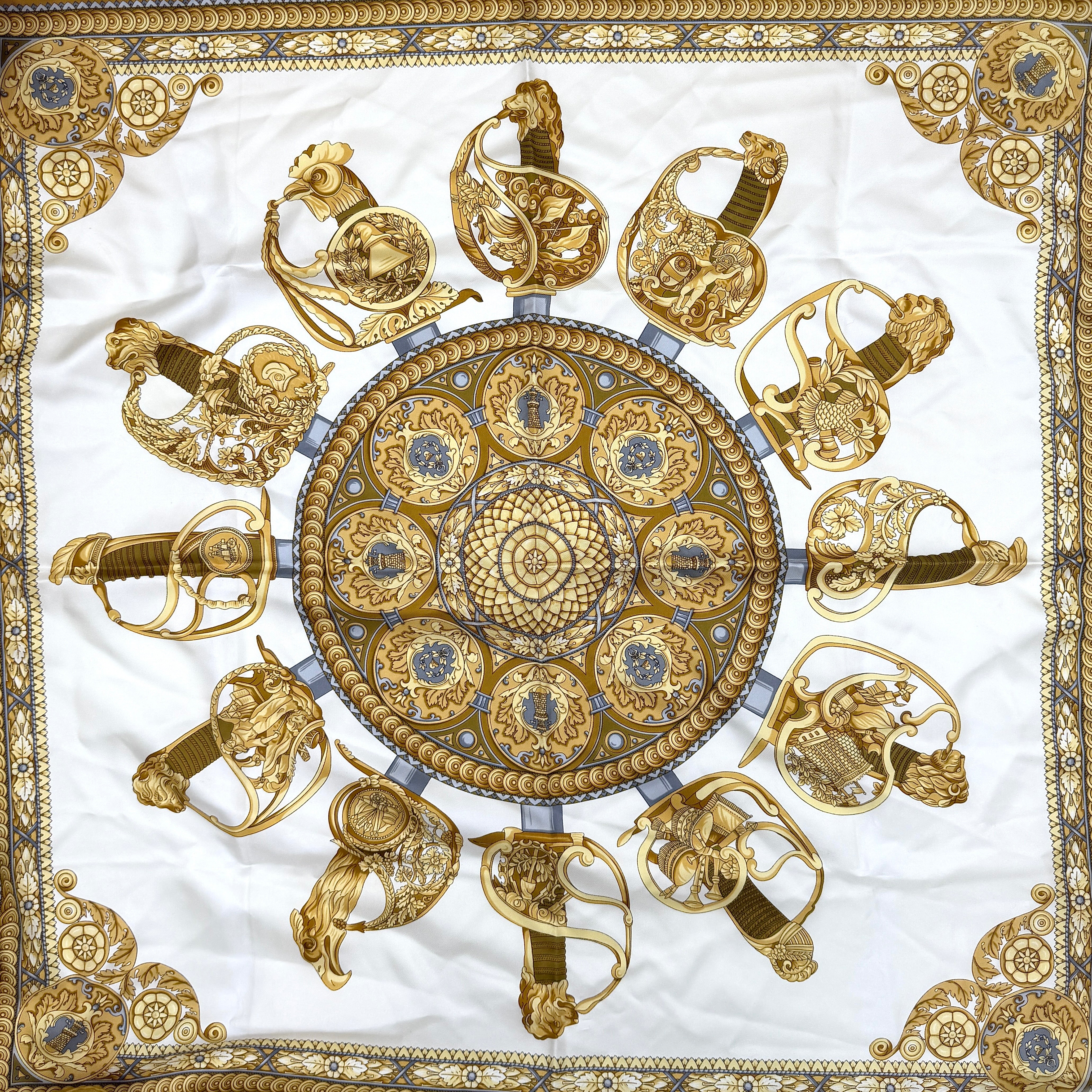 Gucci silk scarf in gold and white, featuring an intricate equestrian medallion design with ornate sabres and classical borders.