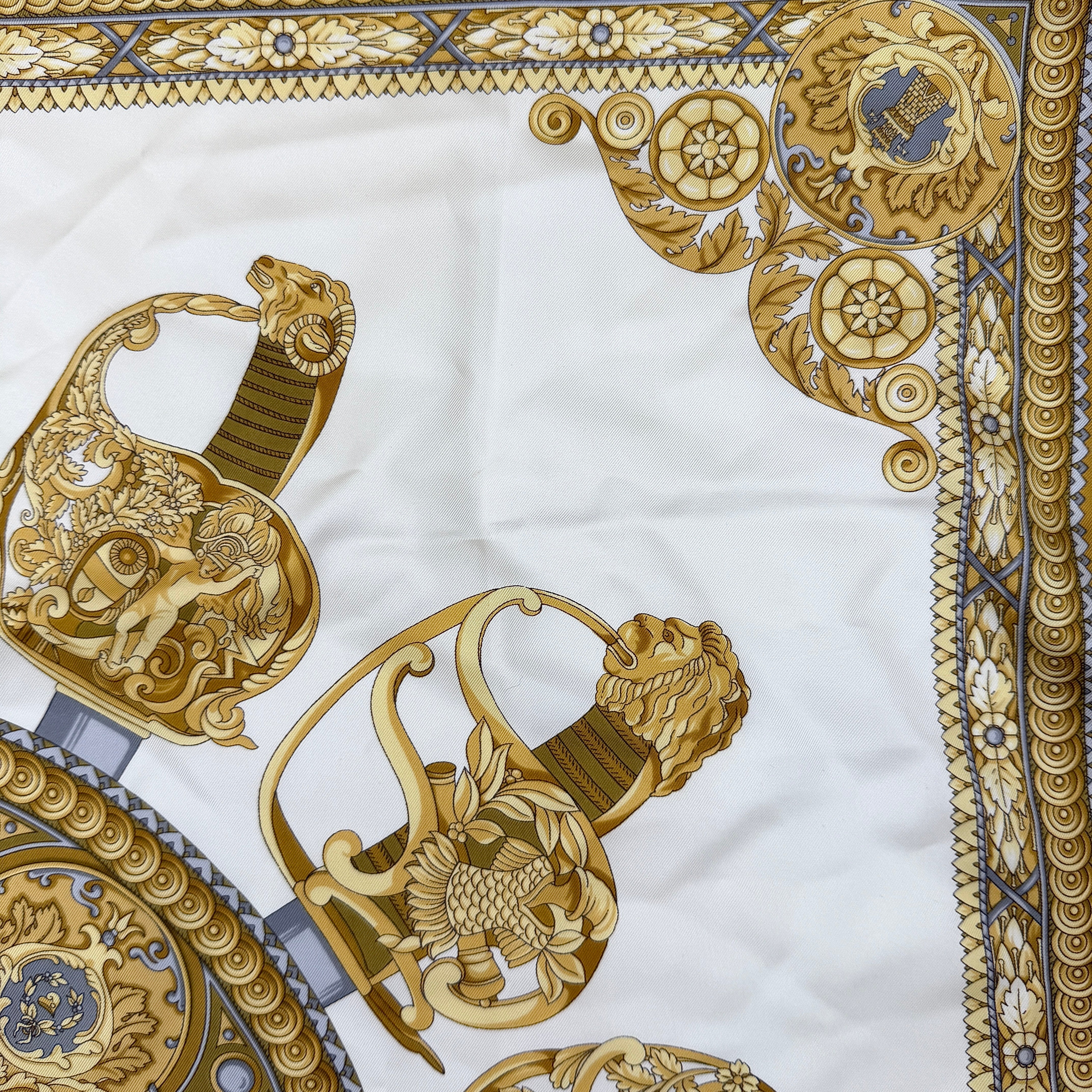 Gucci silk scarf in gold and white, featuring an intricate equestrian medallion design with ornate sabres and classical borders.