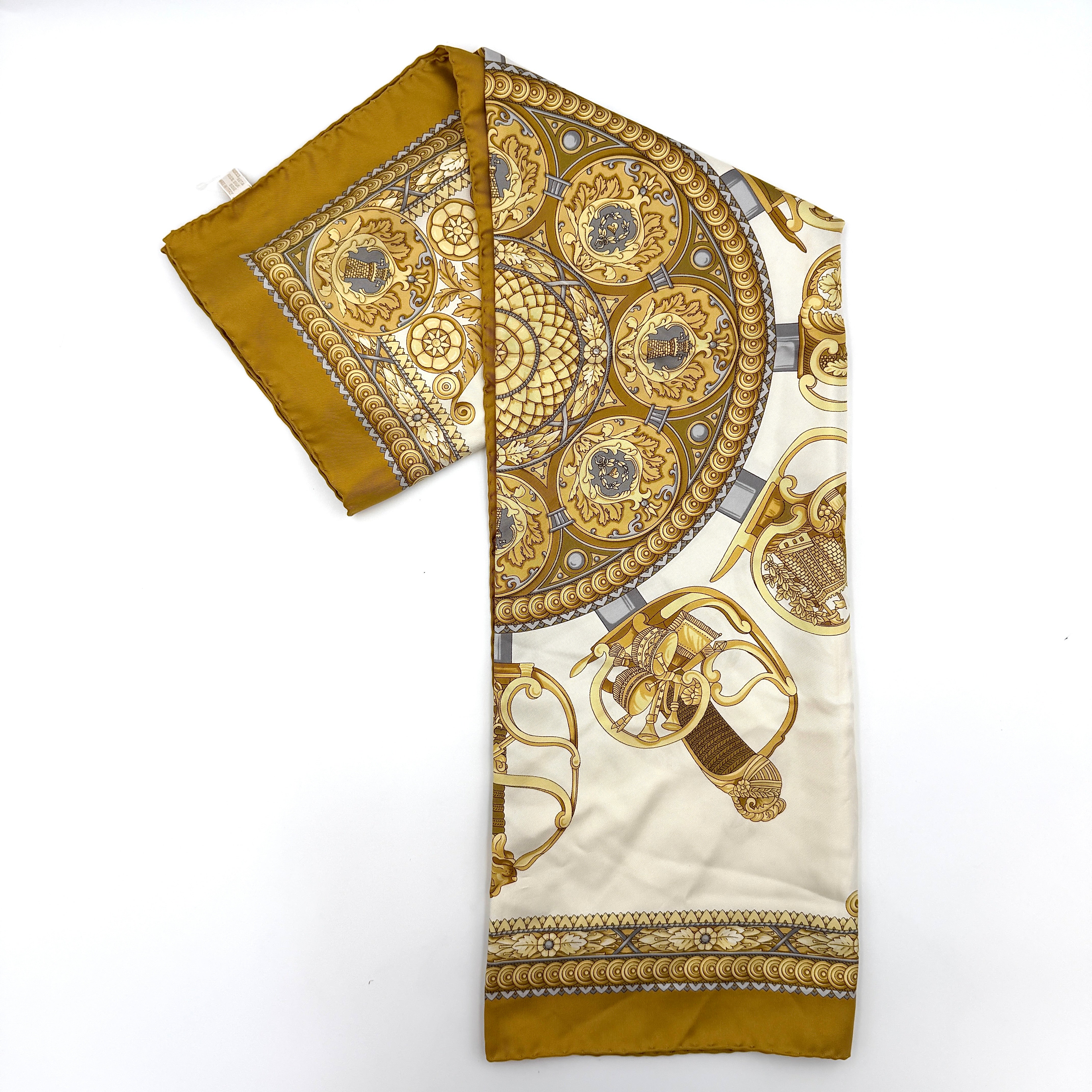 Gucci silk scarf in gold and white, featuring an intricate equestrian medallion design with ornate sabres and classical borders.
