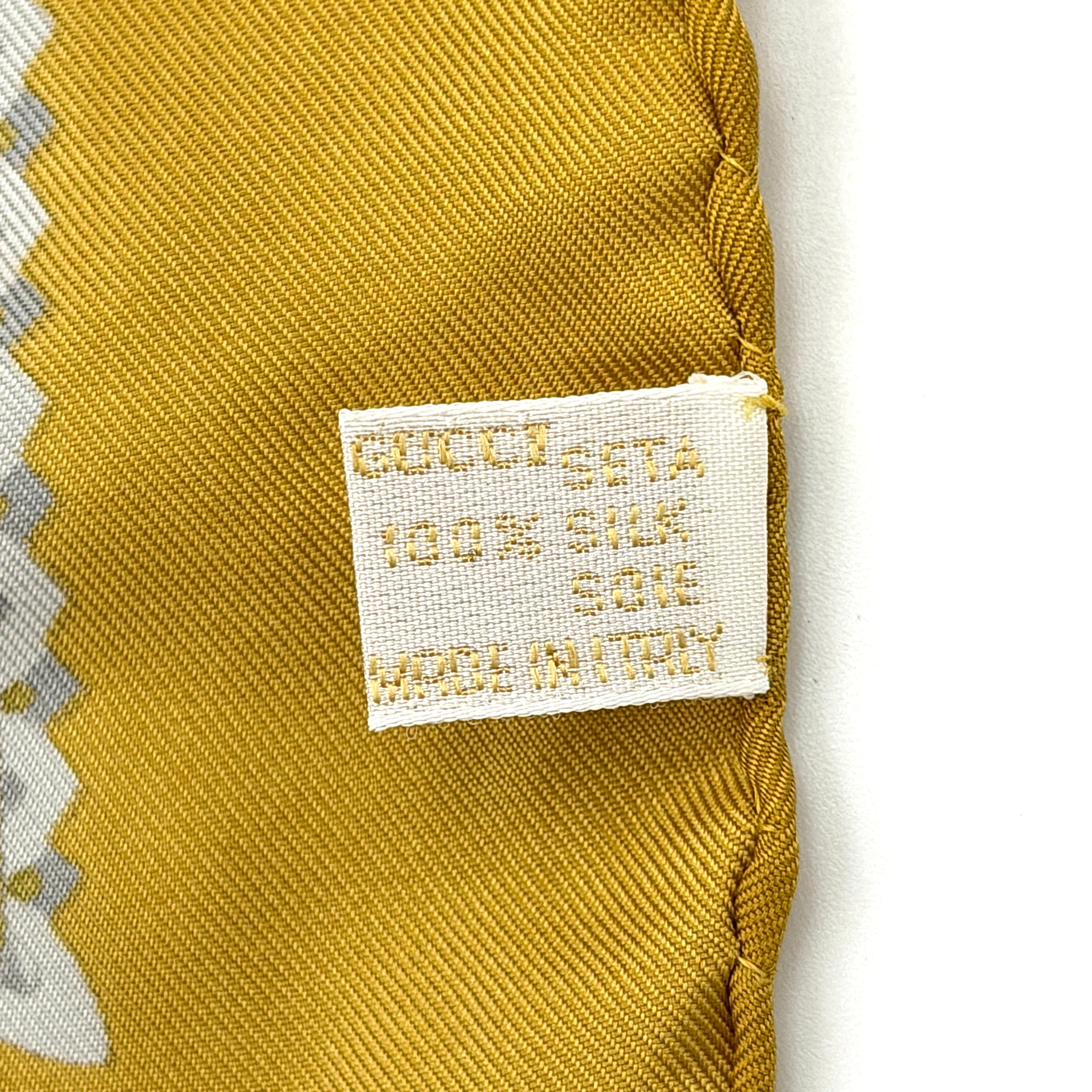 Gucci silk scarf in gold and white, featuring an intricate equestrian medallion design with ornate sabres and classical borders.