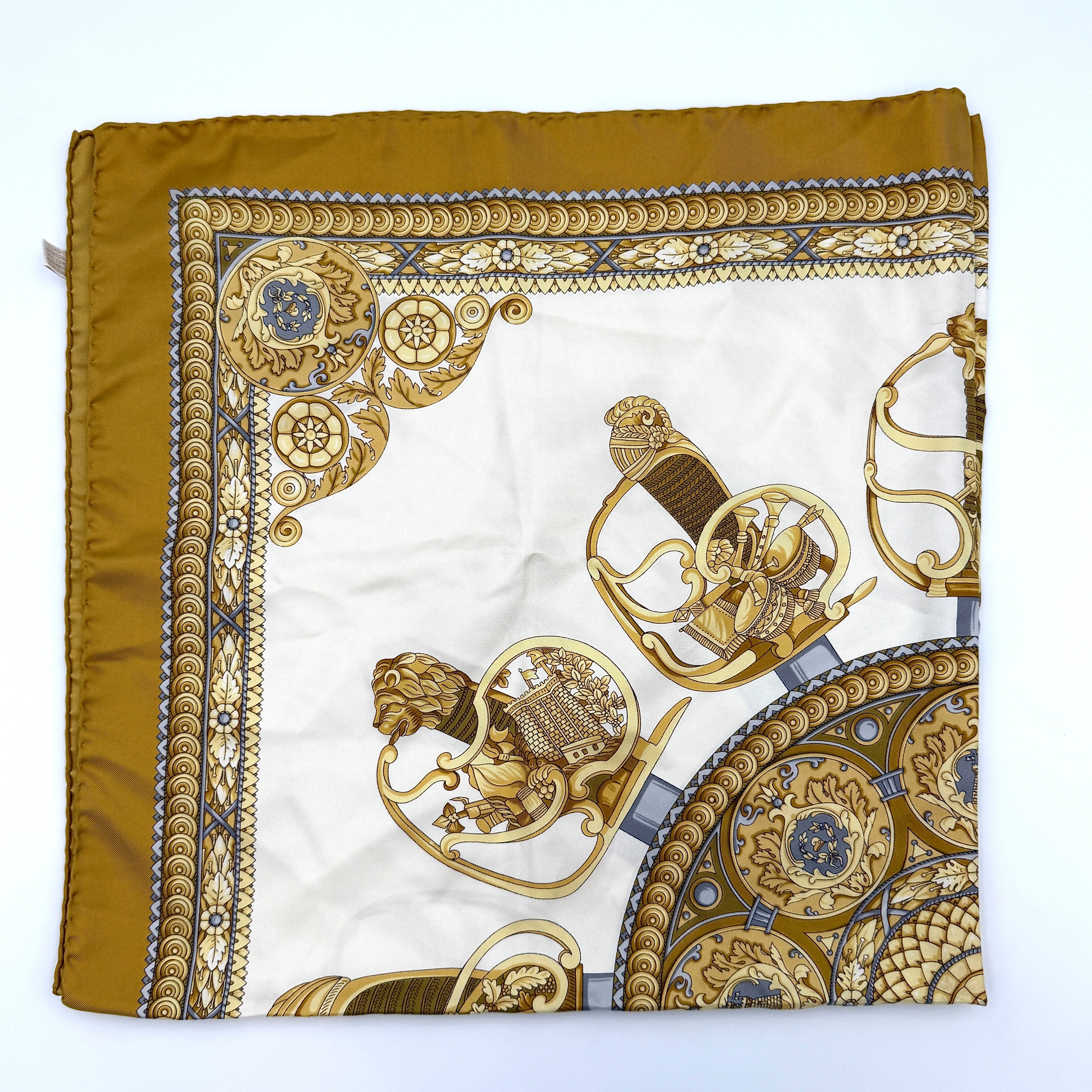 Gucci silk scarf in gold and white, featuring an intricate equestrian medallion design with ornate sabres and classical borders.