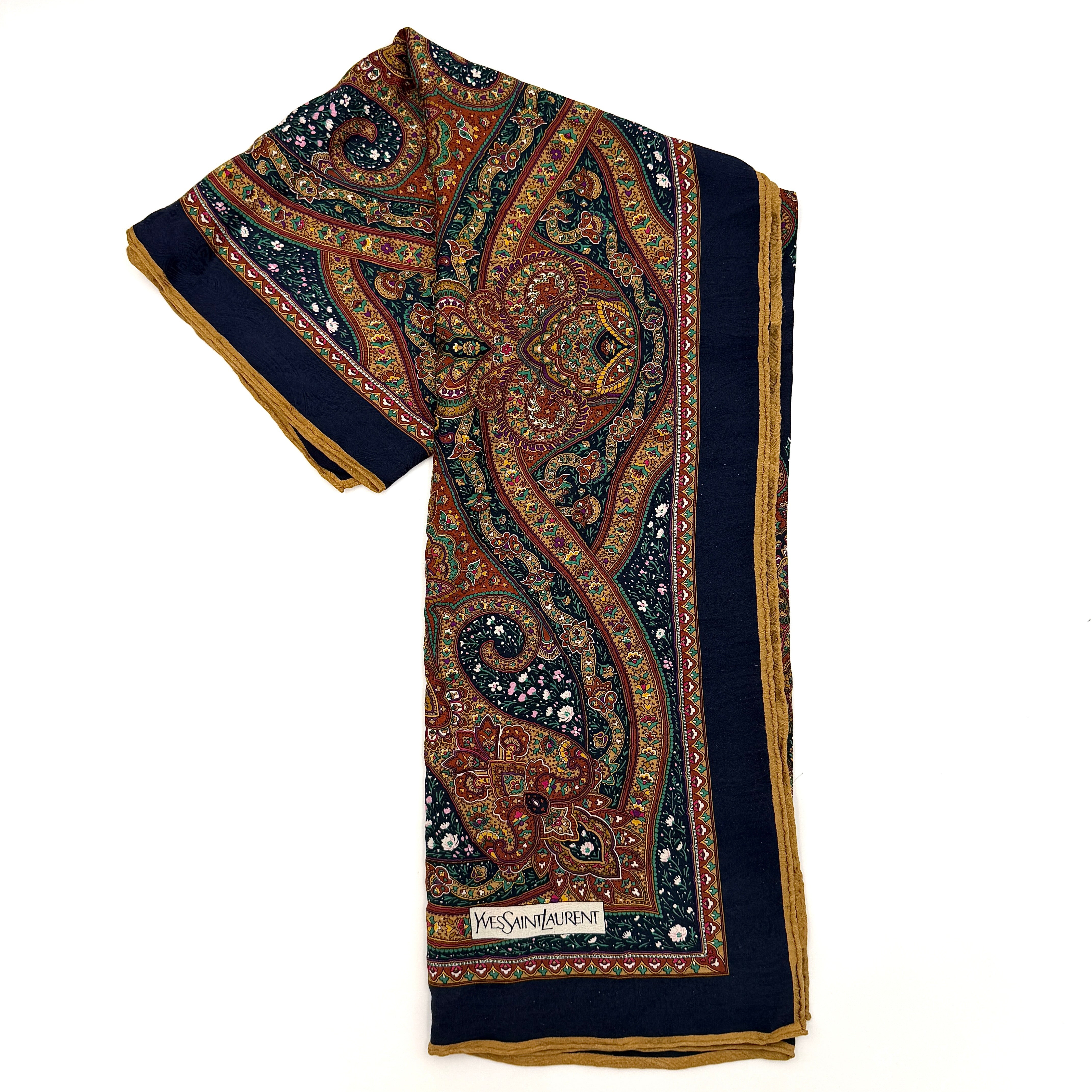 A Saint Laurent cotton scarf in multicolour paisley, elegantly folded to reveal its intricate pattern and ochre border.