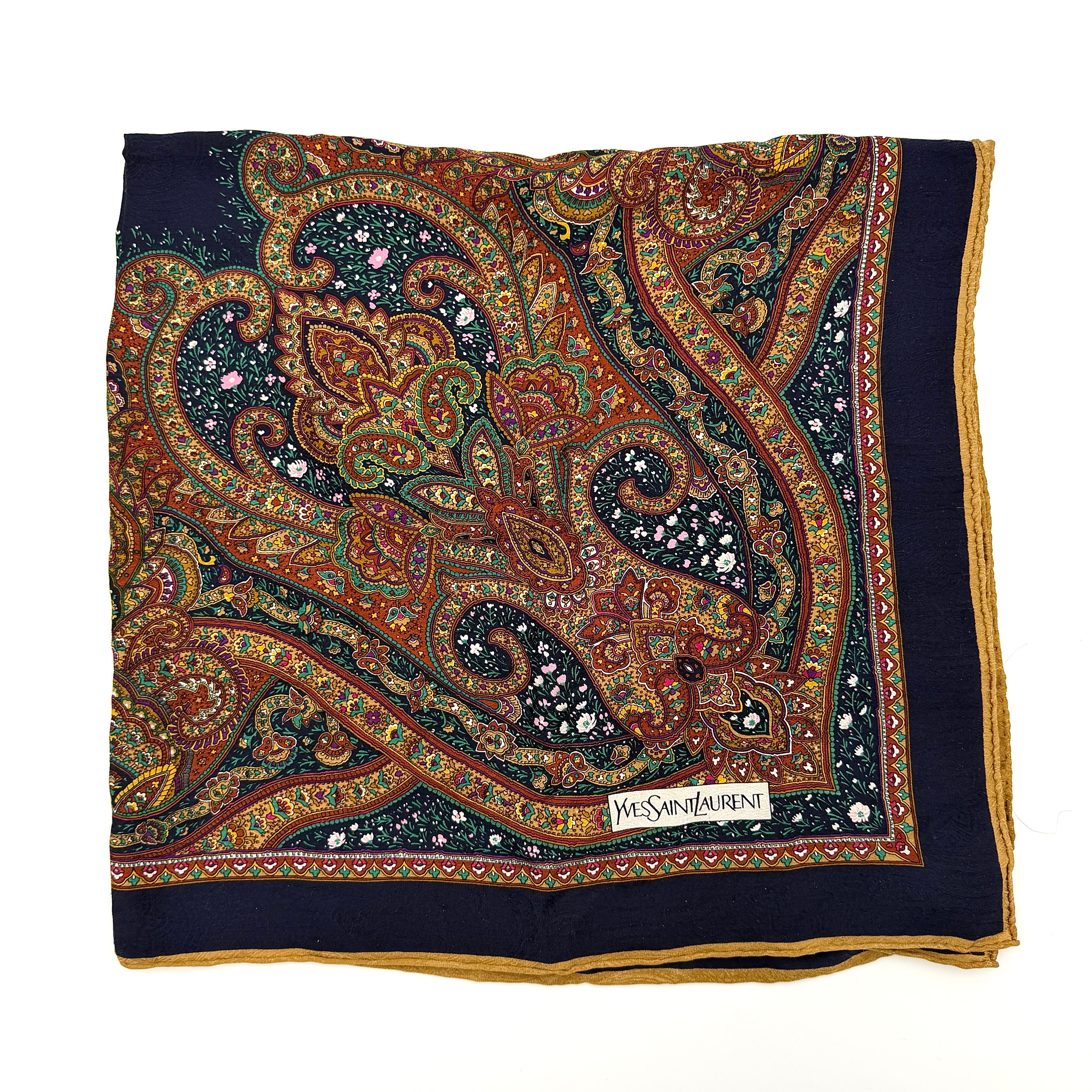 A Saint Laurent cotton scarf in multicolour paisley, elegantly folded to reveal its intricate pattern and ochre border.