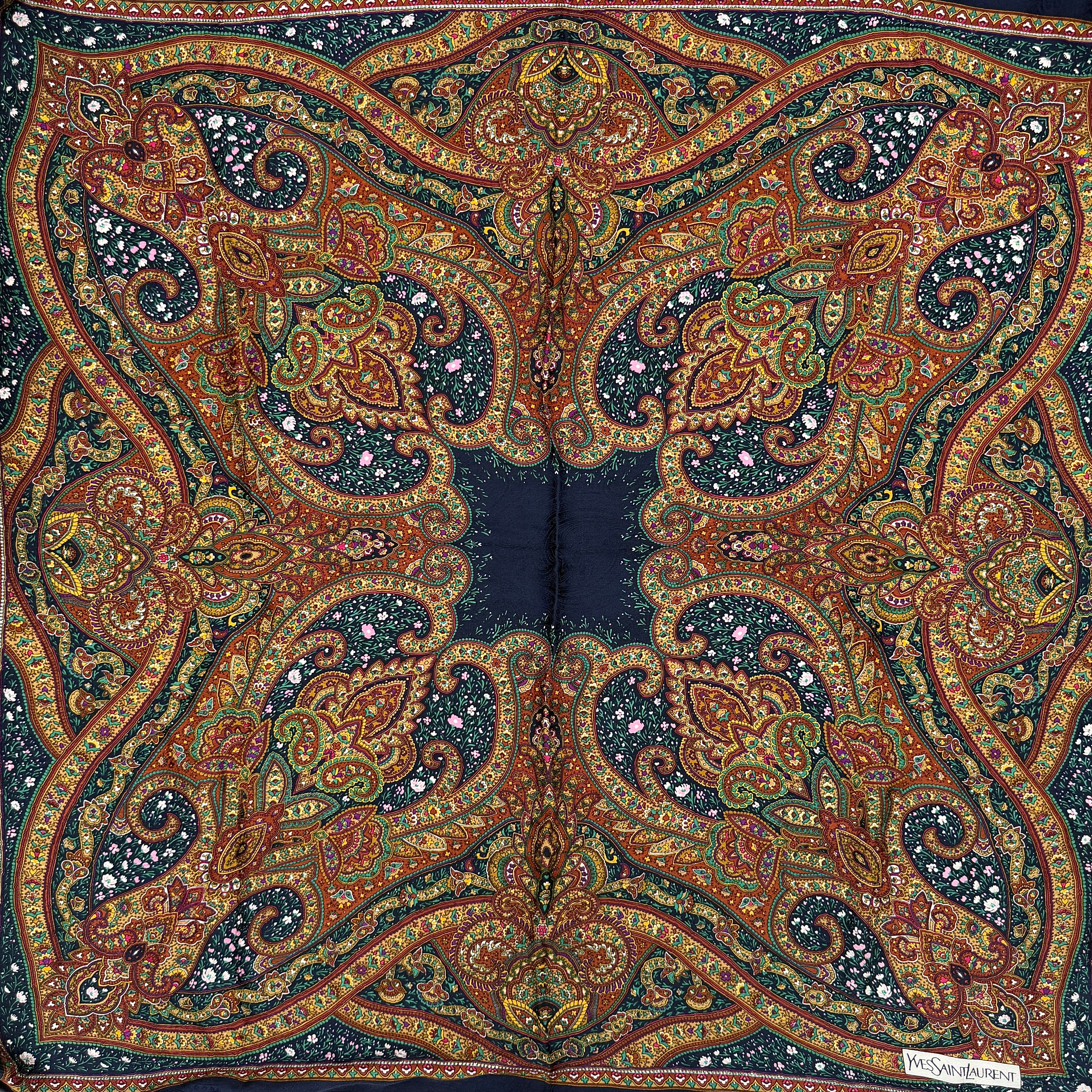 A Saint Laurent cotton scarf in multicolour paisley, elegantly folded to reveal its intricate pattern and ochre border.