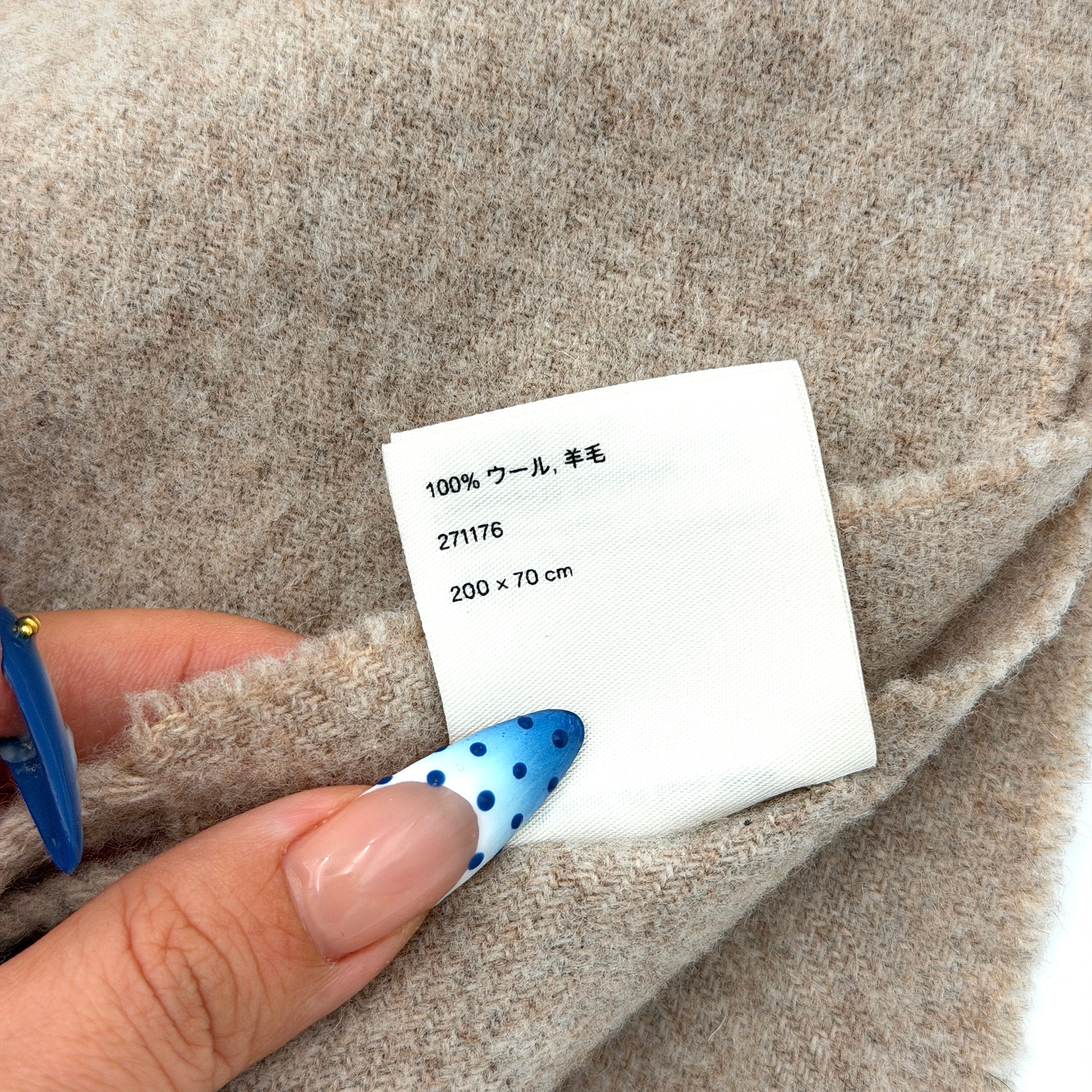 Acne Studios wool scarf in soft light brown with a fringed edge and signature label at the hem.