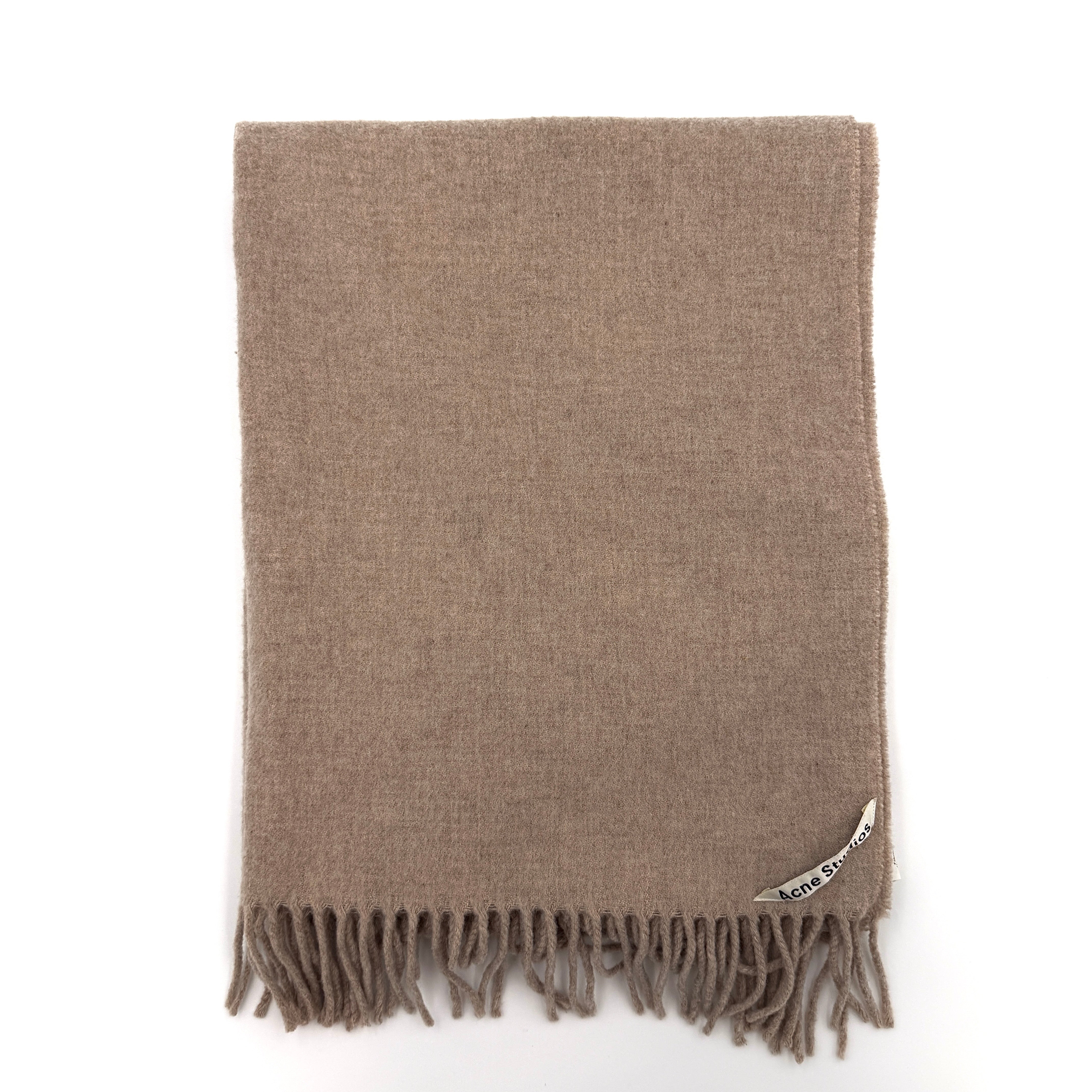 Acne Studios wool scarf in soft light brown with a fringed edge and signature label at the hem.