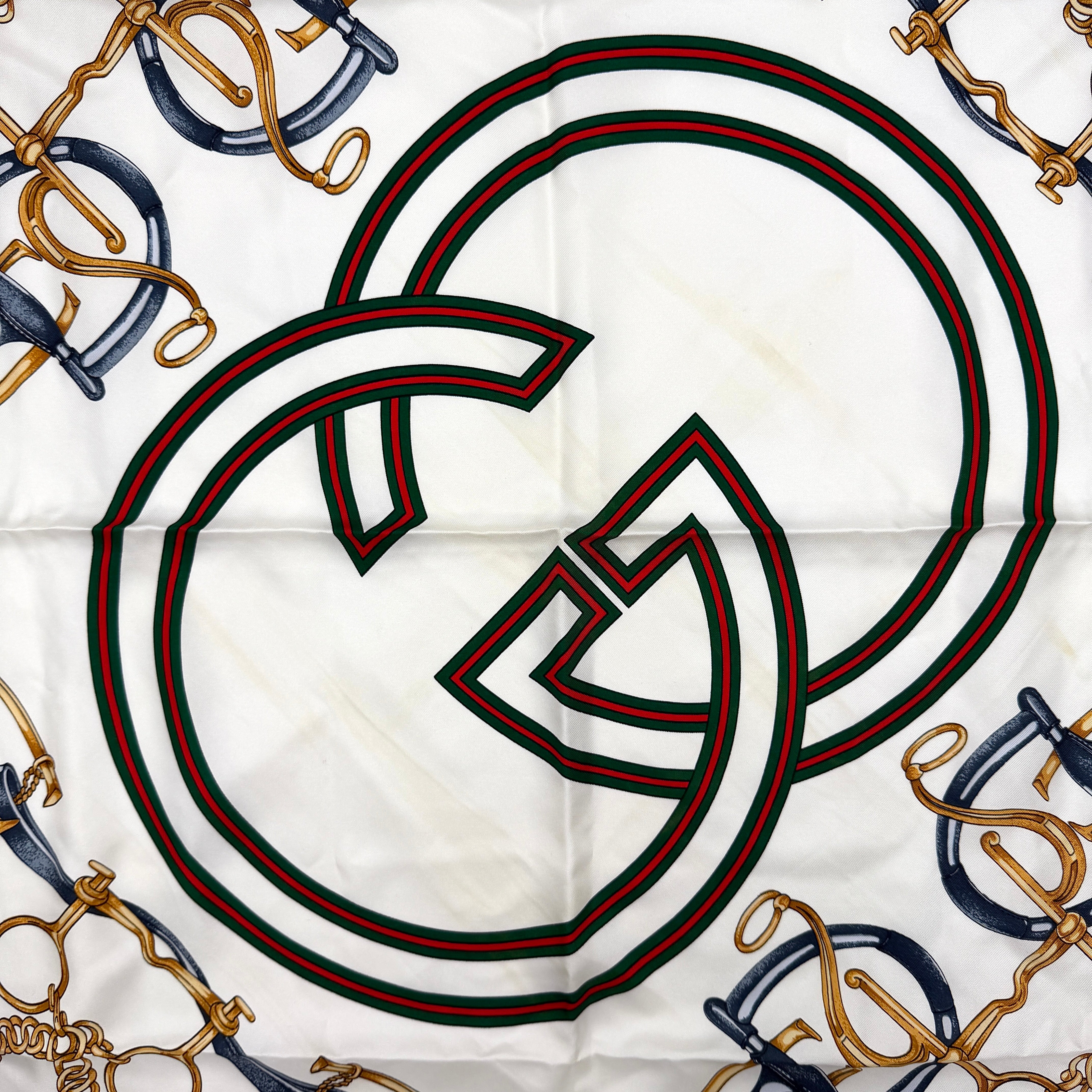 Gucci silk scarf with equestrian horsebit print, navy borders, and large GG logo displayed against a white background.