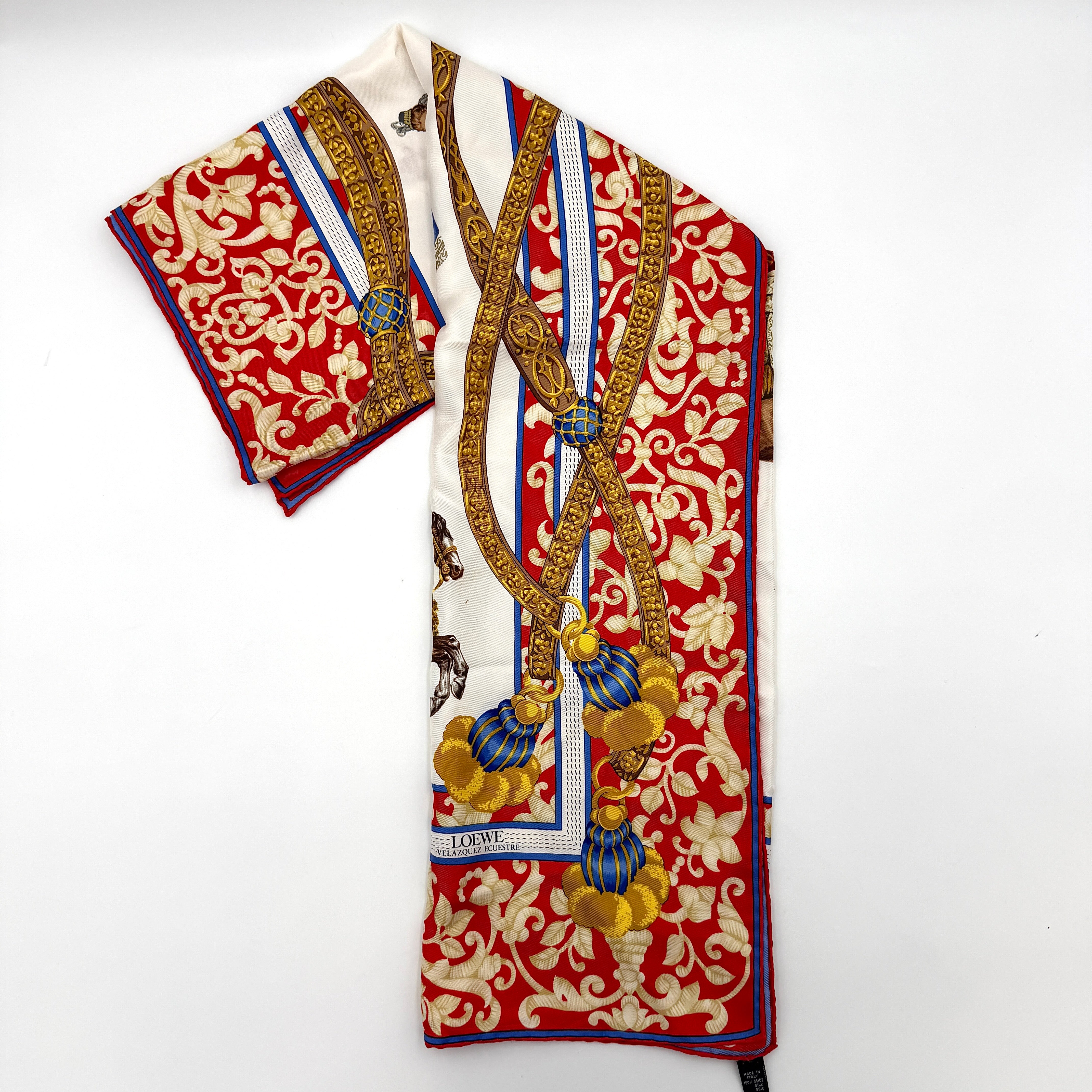 Loewe Velazquez Ecuestre silk scarf adorned with ornate red and gold baroque motifs and equestrian figures in rich multicolor.