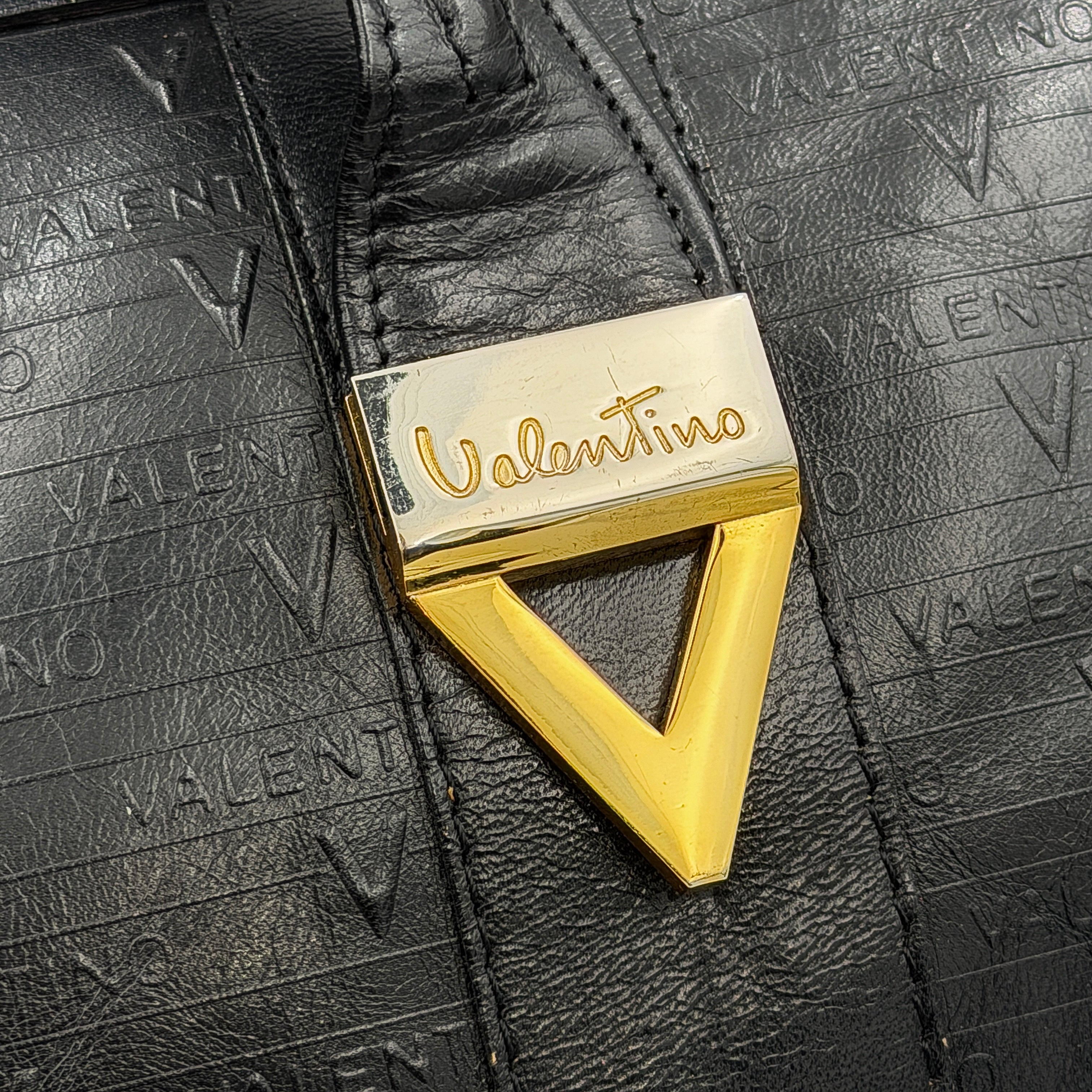 Valentino Monogram Boston Bag in black embossed leather with gold-tone V hardware and dual top handles.
