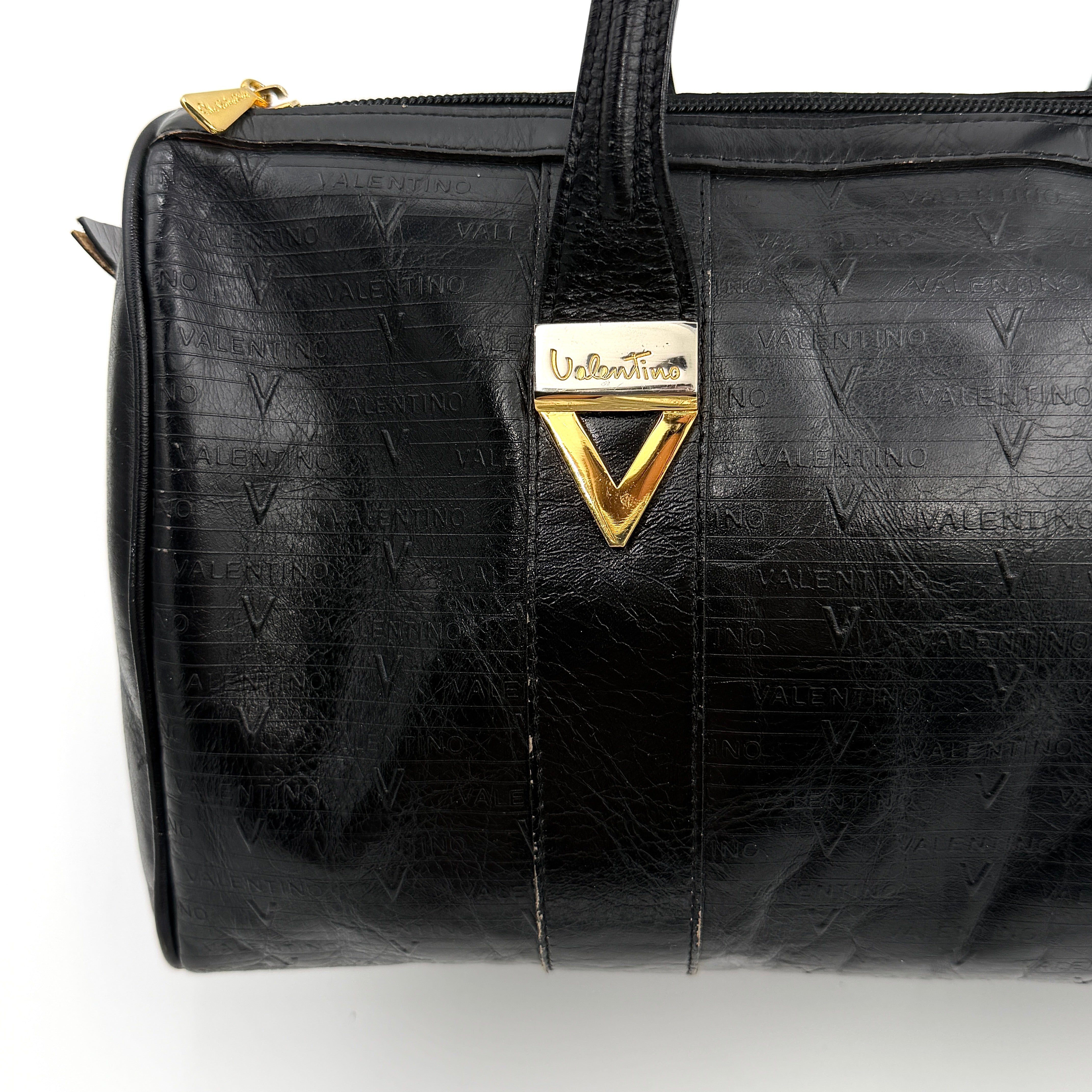 Valentino Monogram Boston Bag in black embossed leather with gold-tone V hardware and dual top handles.