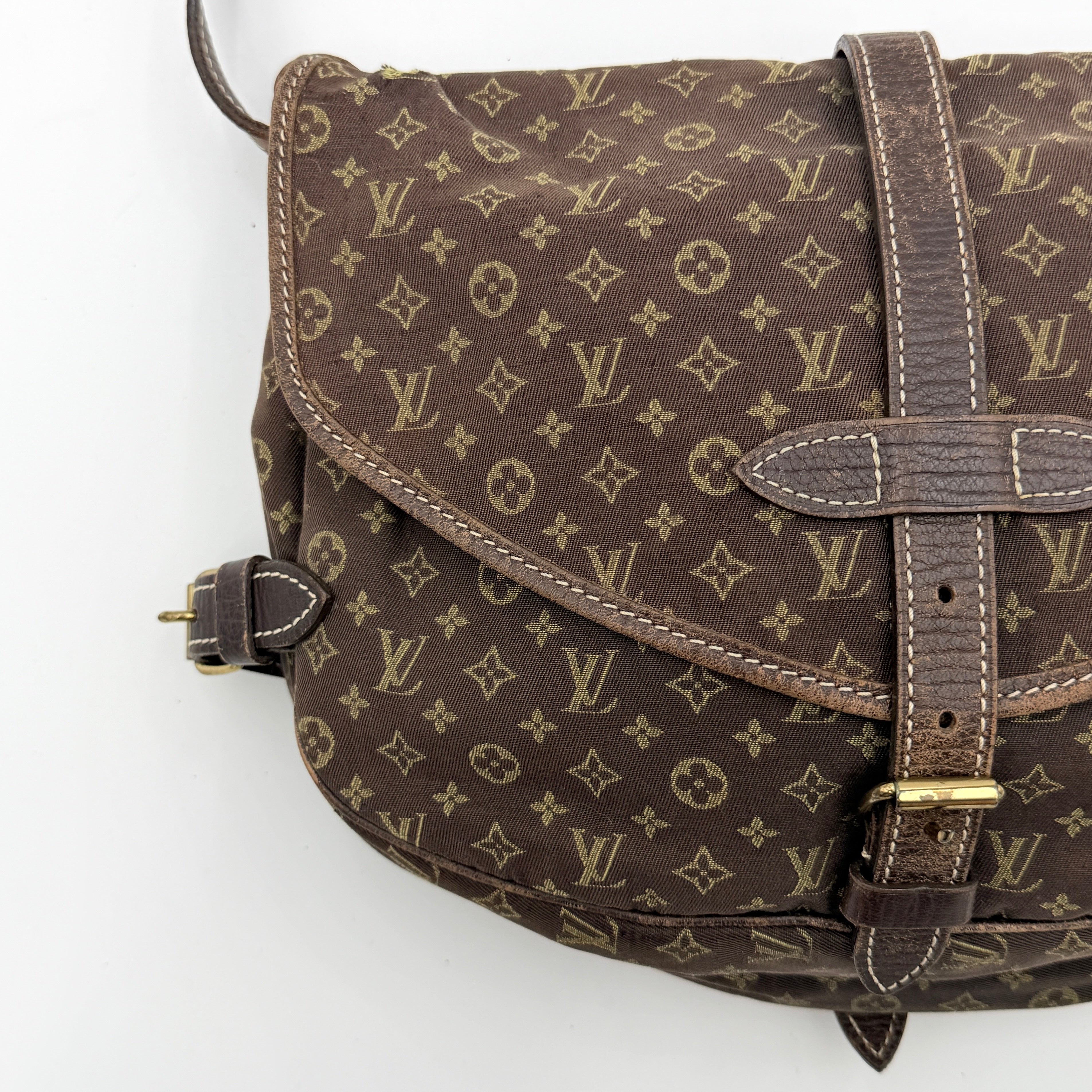 Louis Vuitton Monogram Mini Lin Saumur 30 in brown canvas with monogram pattern and leather buckled strap, photographed with the crossbody strap extended.
