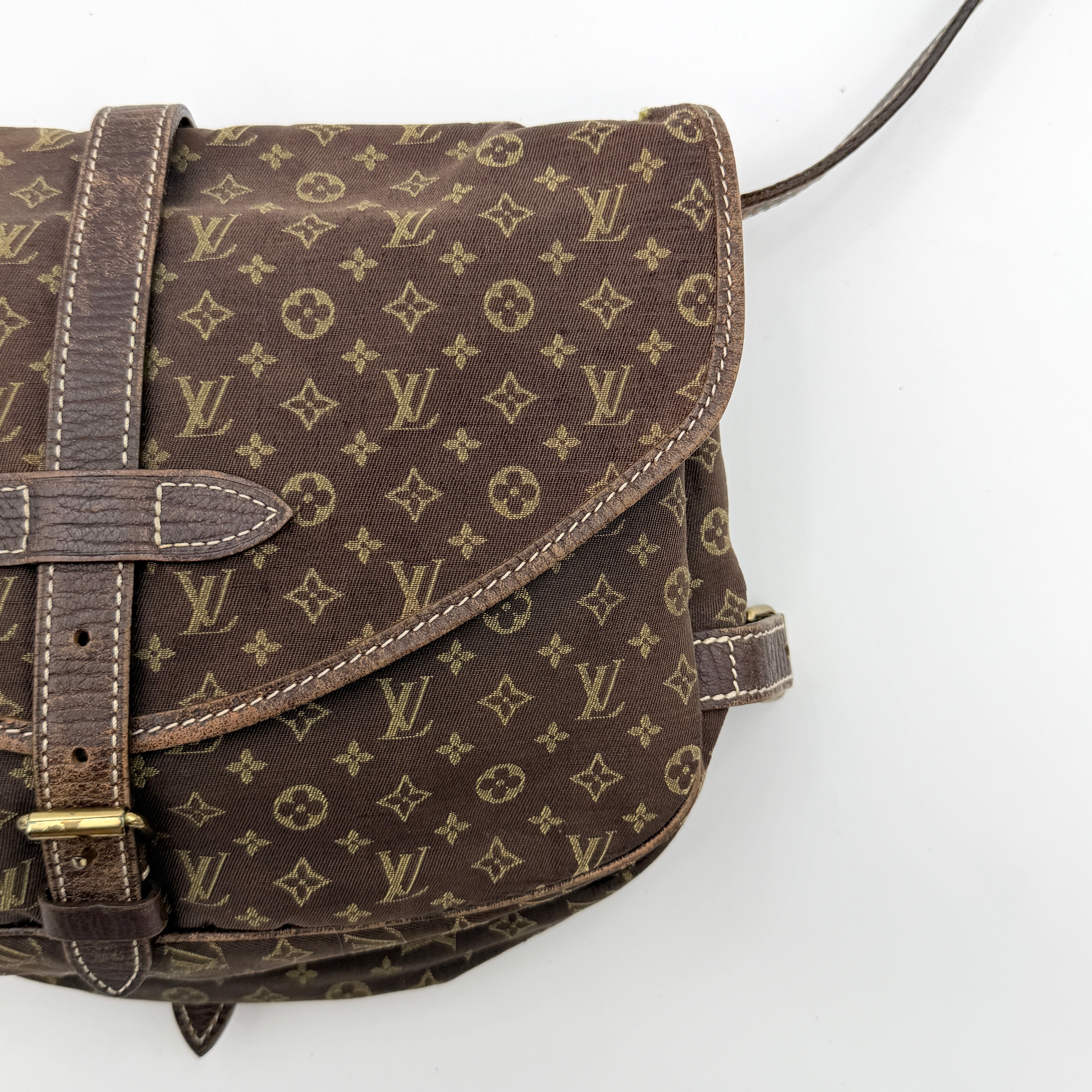 Louis Vuitton Monogram Mini Lin Saumur 30 in brown canvas with monogram pattern and leather buckled strap, photographed with the crossbody strap extended.