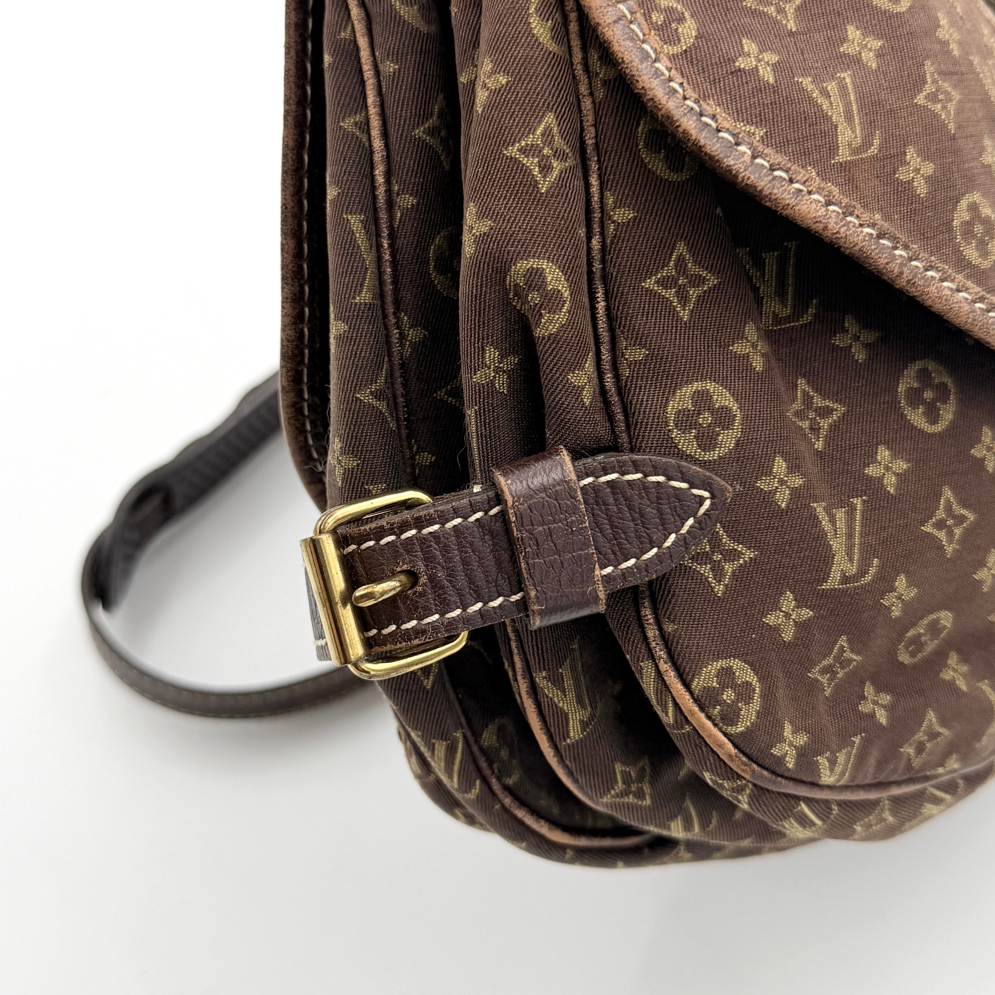 Louis Vuitton Monogram Mini Lin Saumur 30 in brown canvas with monogram pattern and leather buckled strap, photographed with the crossbody strap extended.