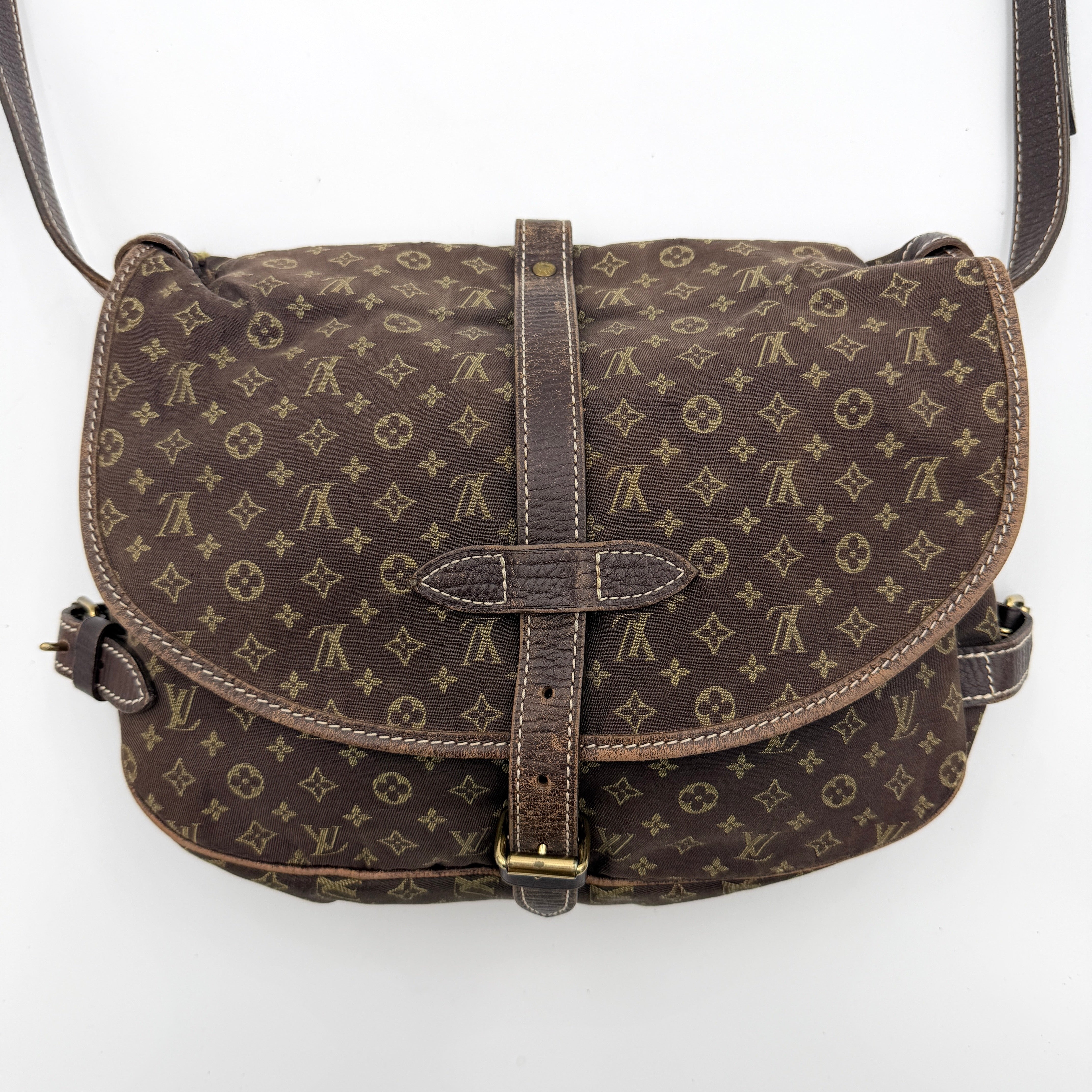 Louis Vuitton Monogram Mini Lin Saumur 30 in brown canvas with monogram pattern and leather buckled strap, photographed with the crossbody strap extended.