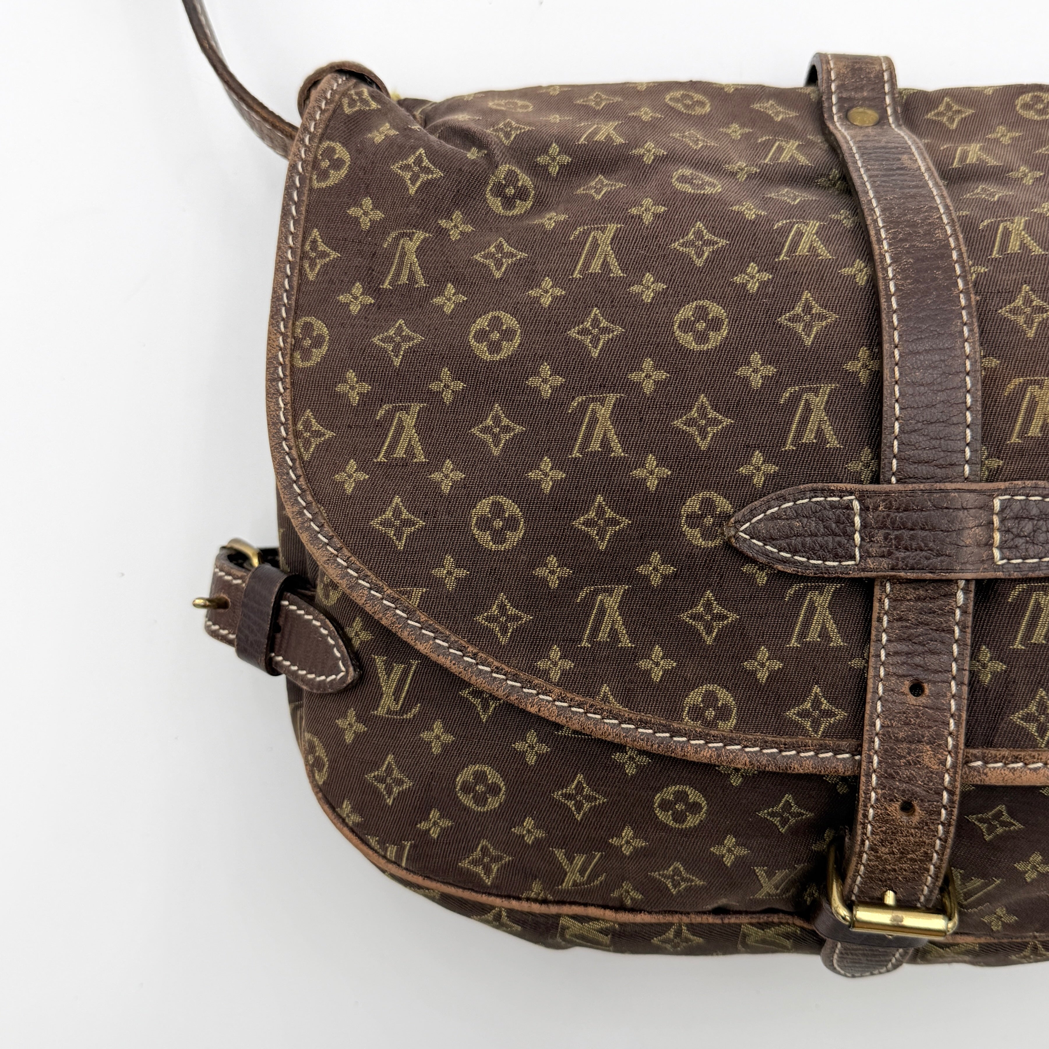 Louis Vuitton Monogram Mini Lin Saumur 30 in brown canvas with monogram pattern and leather buckled strap, photographed with the crossbody strap extended.