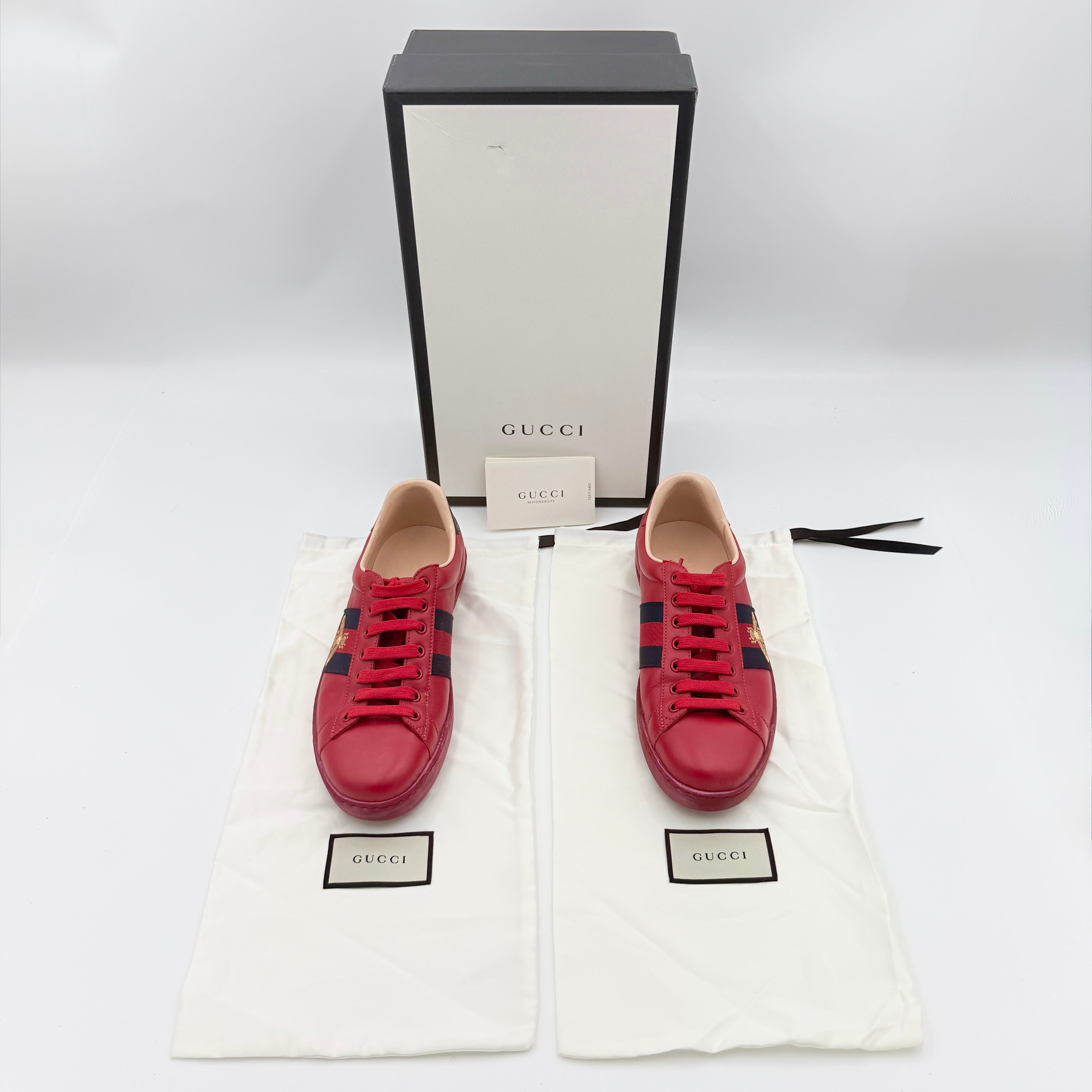 Gucci Ace Embroidered Bee sneakers in red leather with navy and red stripes and gold bee detail.