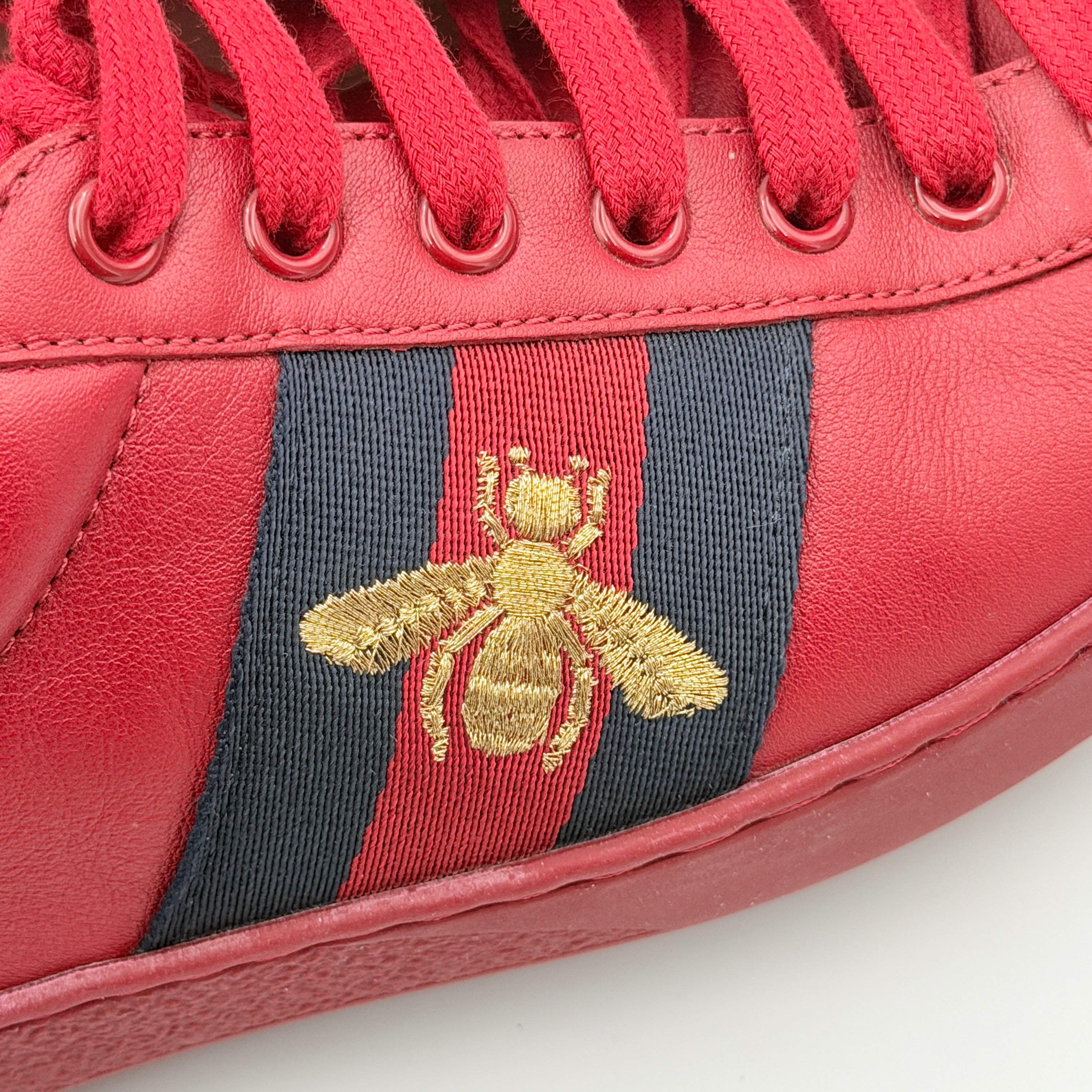 Gucci Ace Embroidered Bee sneakers in red leather with navy and red stripes and gold bee detail.