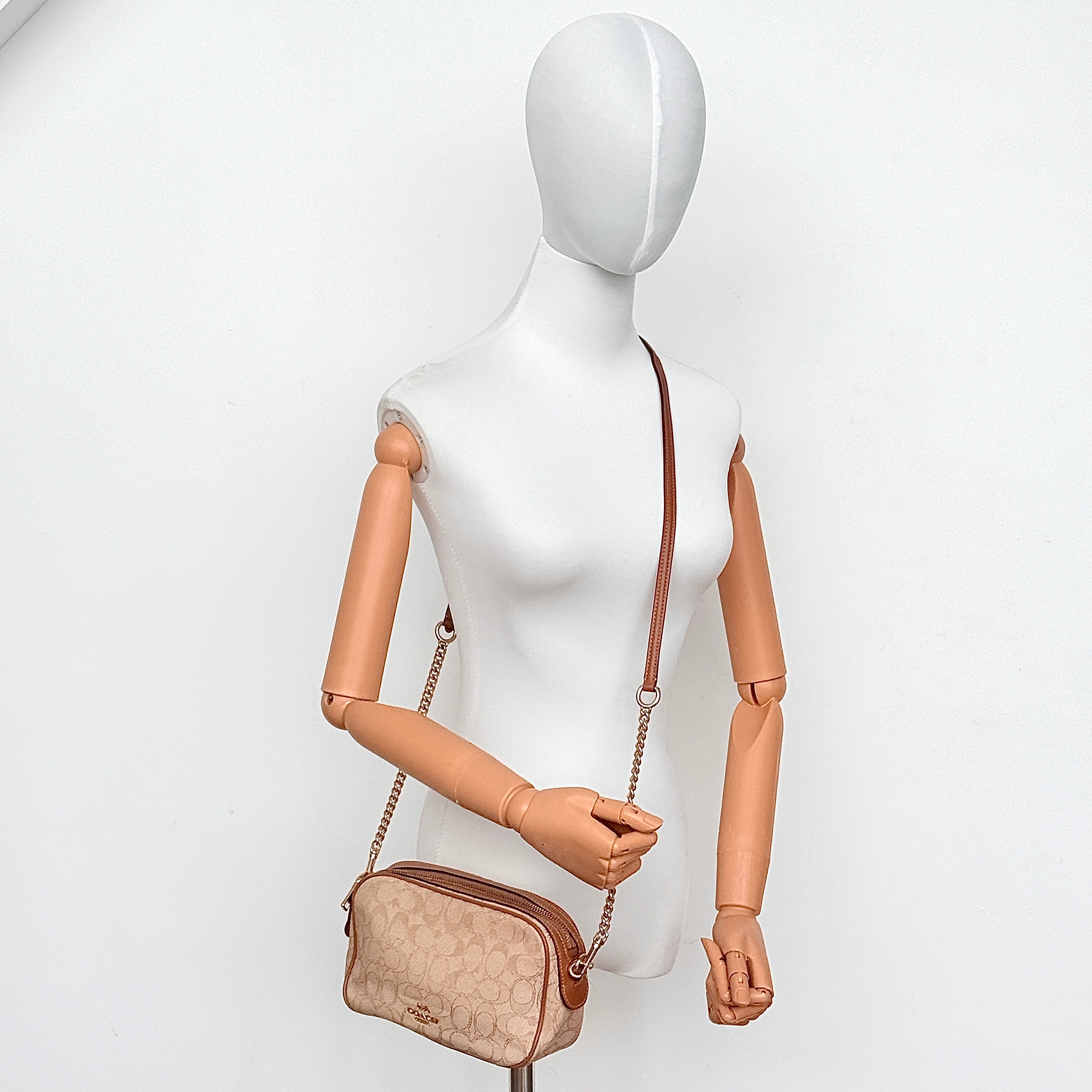 Coach Signature Isla Chain Crossbody in beige and brown canvas with gold-tone chain and leather strap, shown against a white background.