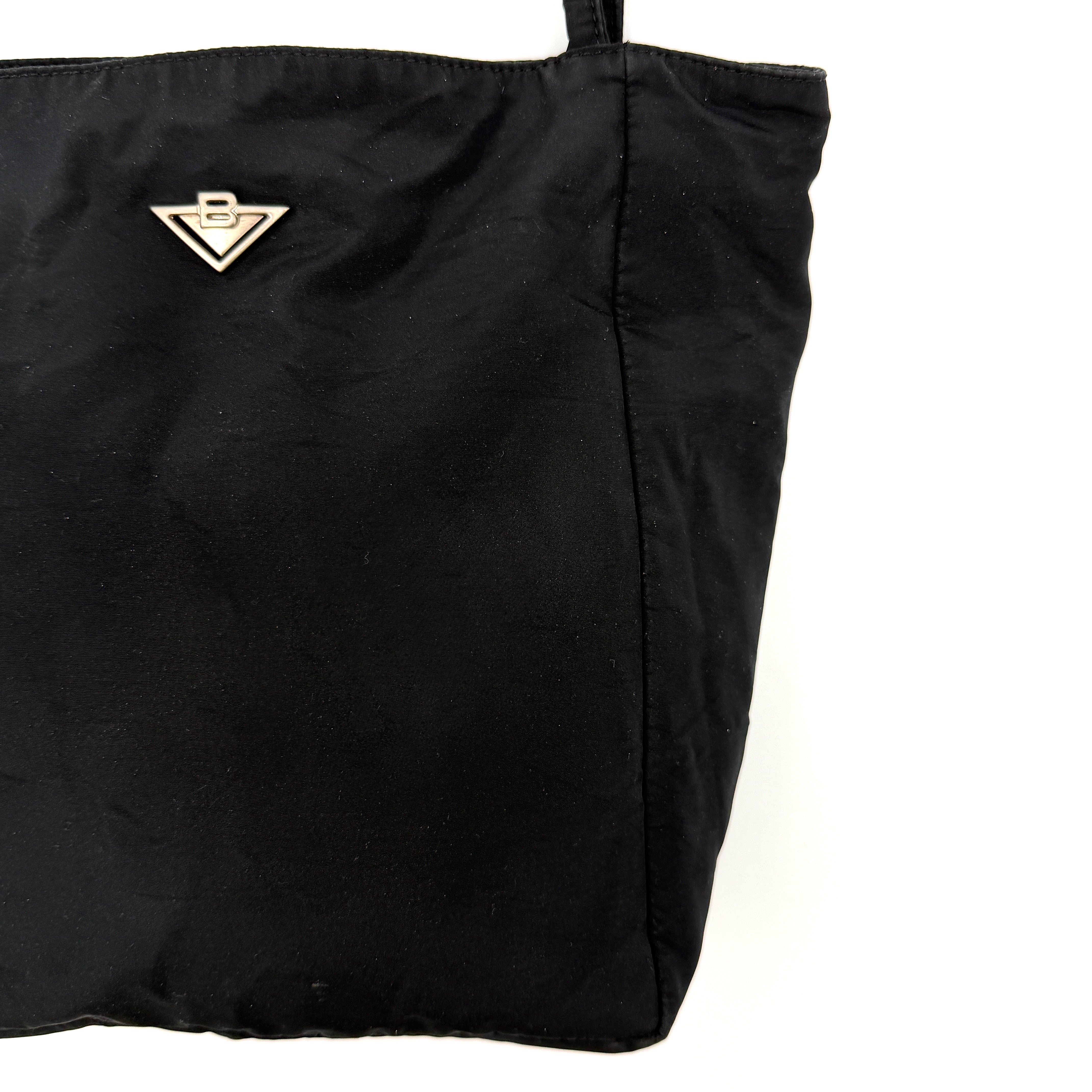 Bottega Veneta black nylon tote with structured double handles and a pale gold-tone logo plaque at the front.