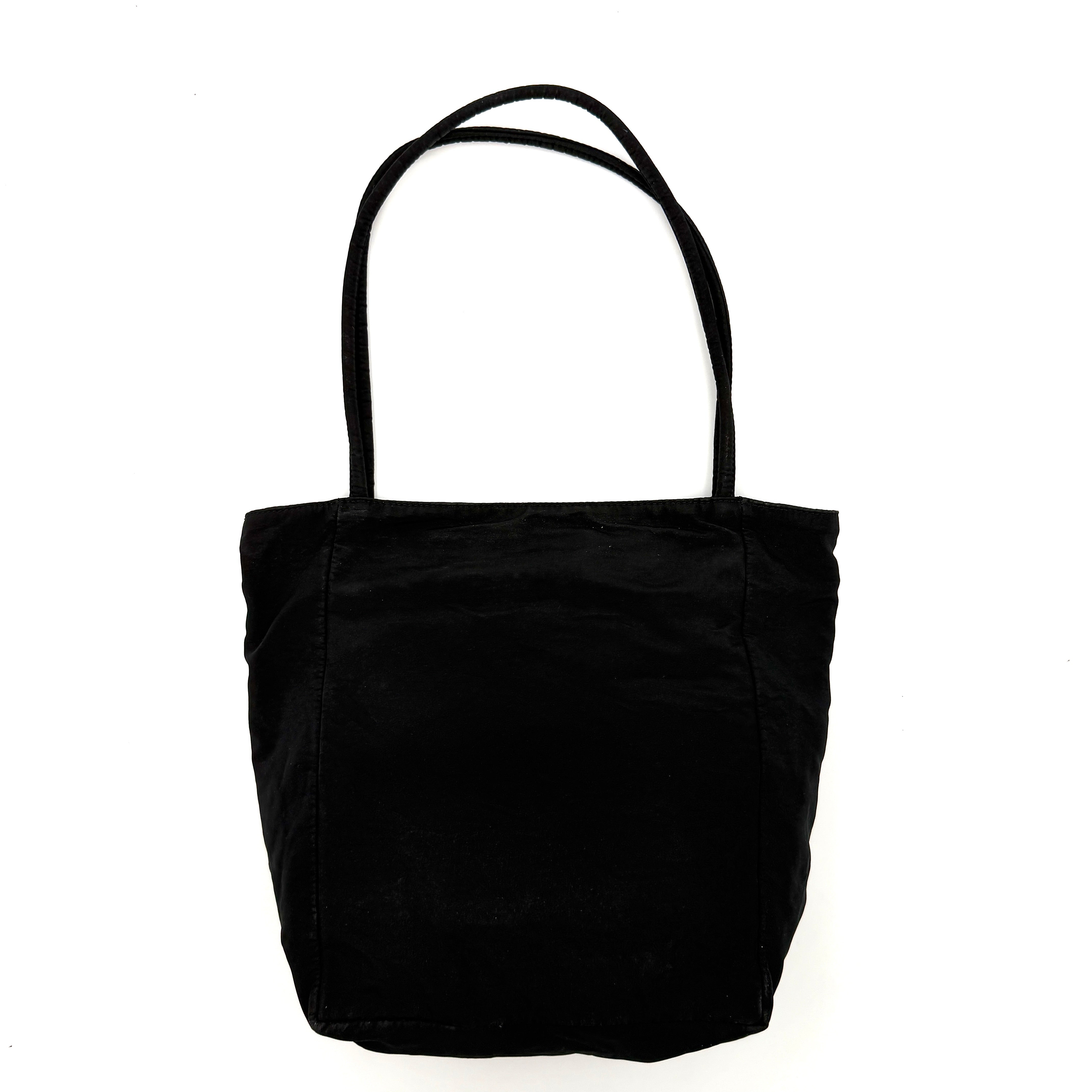 Bottega Veneta black nylon tote with structured double handles and a pale gold-tone logo plaque at the front.