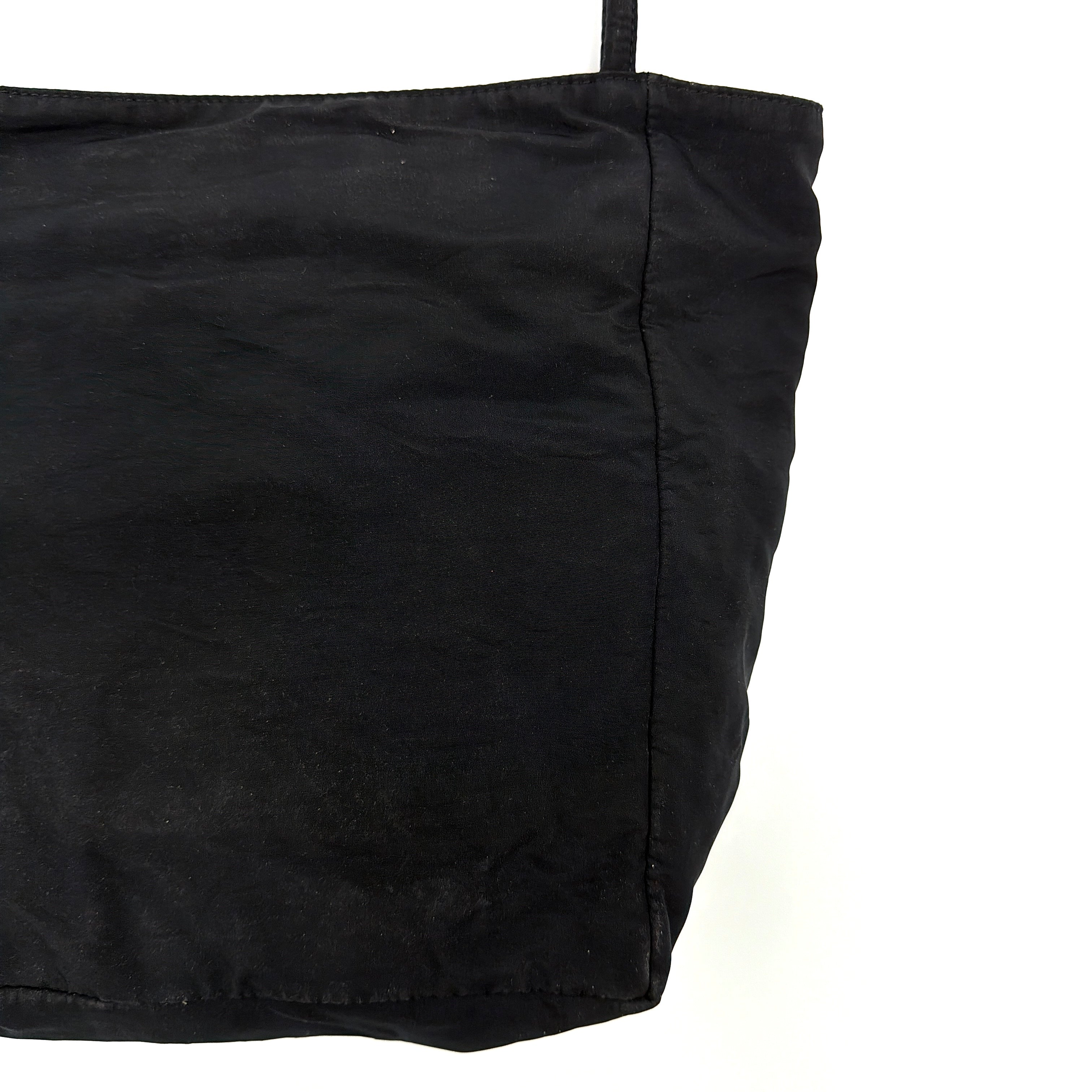 Bottega Veneta black nylon tote with structured double handles and a pale gold-tone logo plaque at the front.
