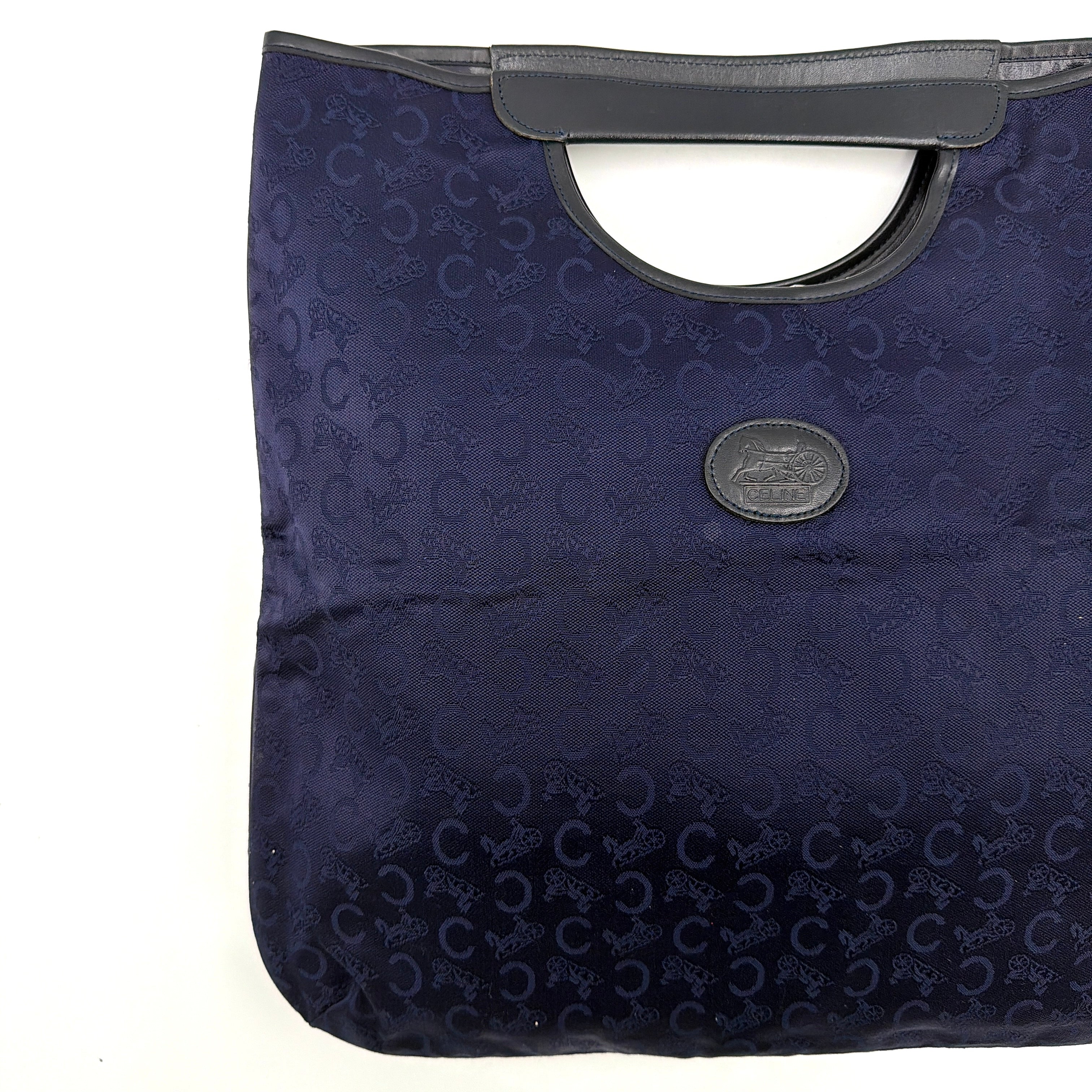 Celine Noevir Macadam Foldover Tote in navy jacquard with carriage motif, leather trim and cutout handles, photographed against a white background.