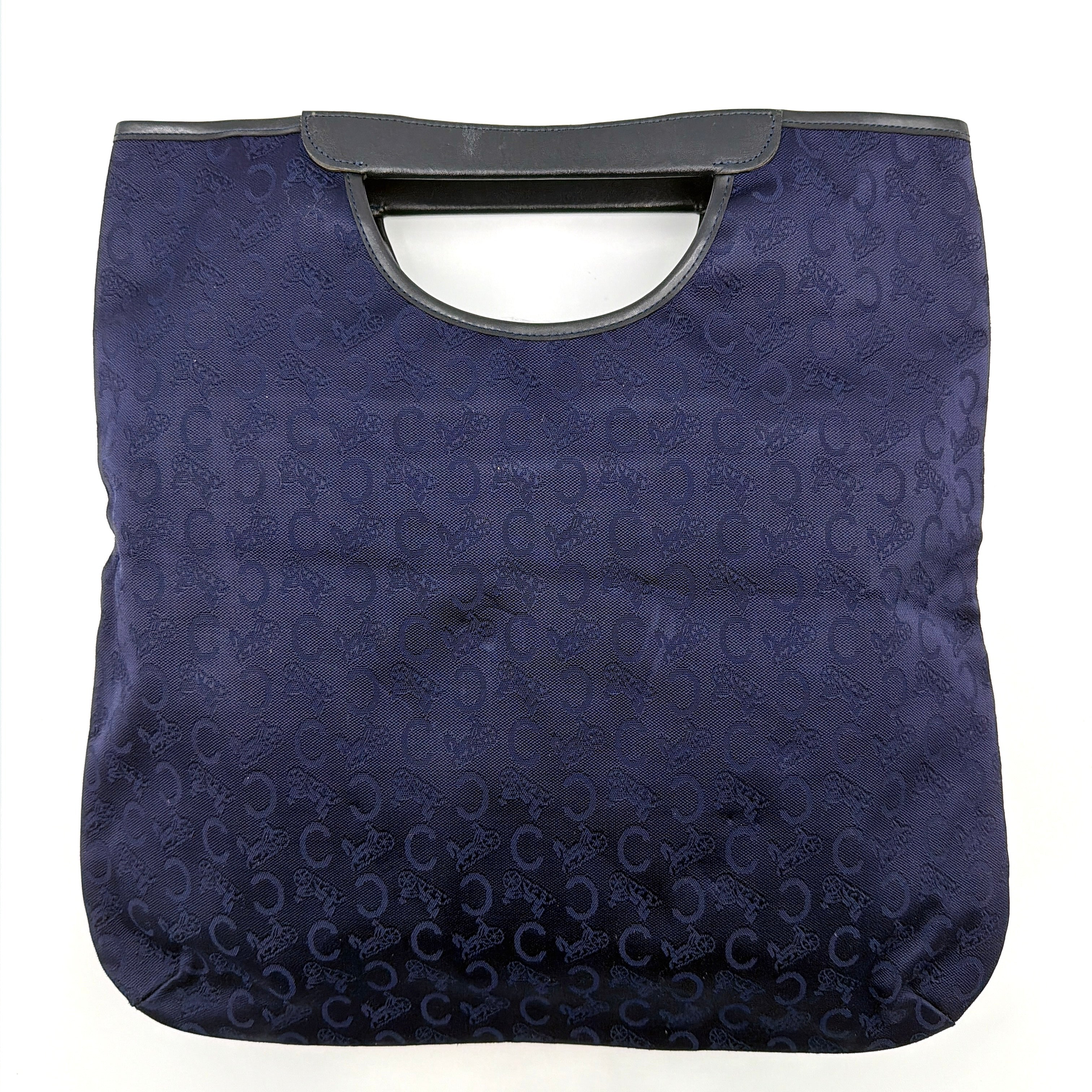 Celine Noevir Macadam Foldover Tote in navy jacquard with carriage motif, leather trim and cutout handles, photographed against a white background.