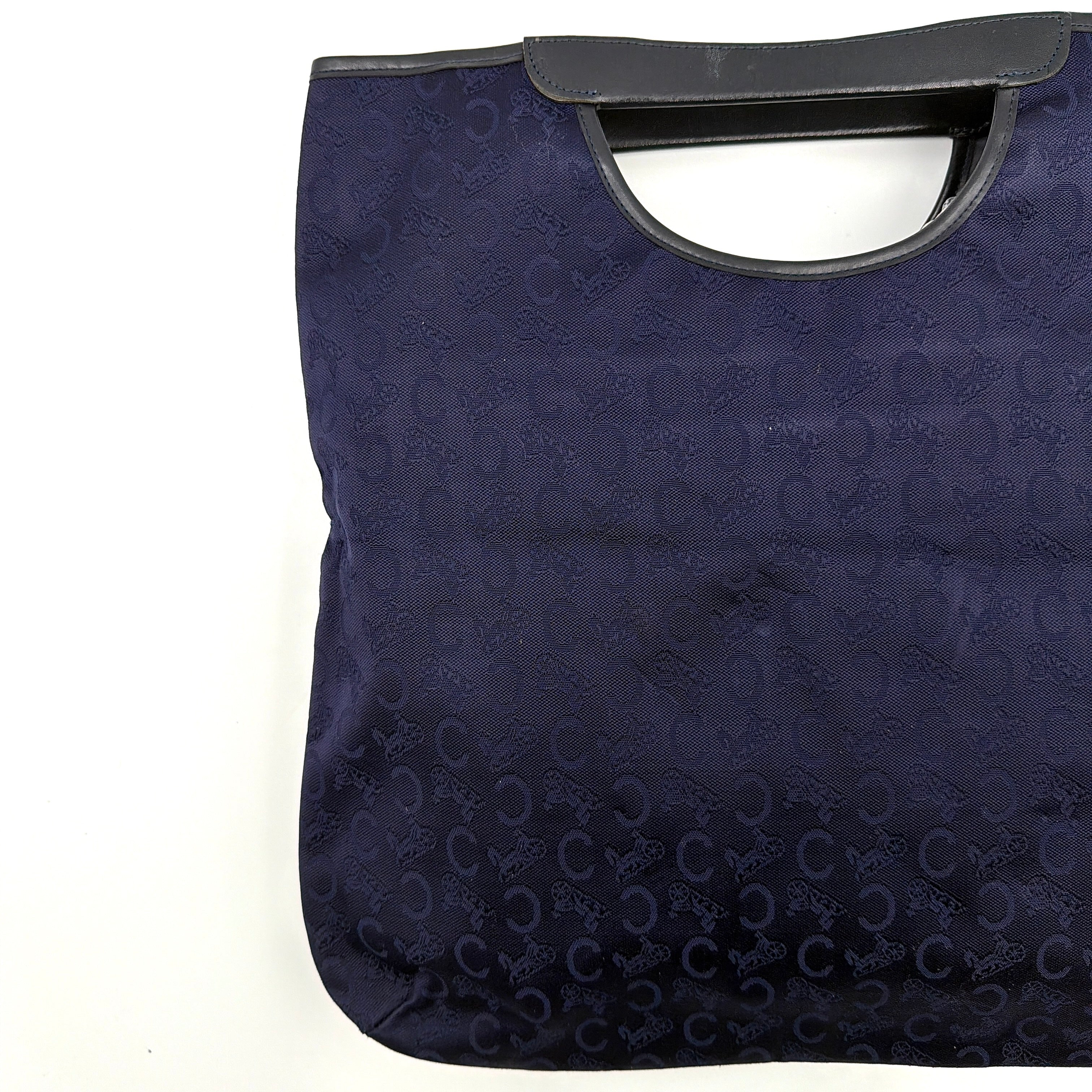 Celine Noevir Macadam Foldover Tote in navy jacquard with carriage motif, leather trim and cutout handles, photographed against a white background.