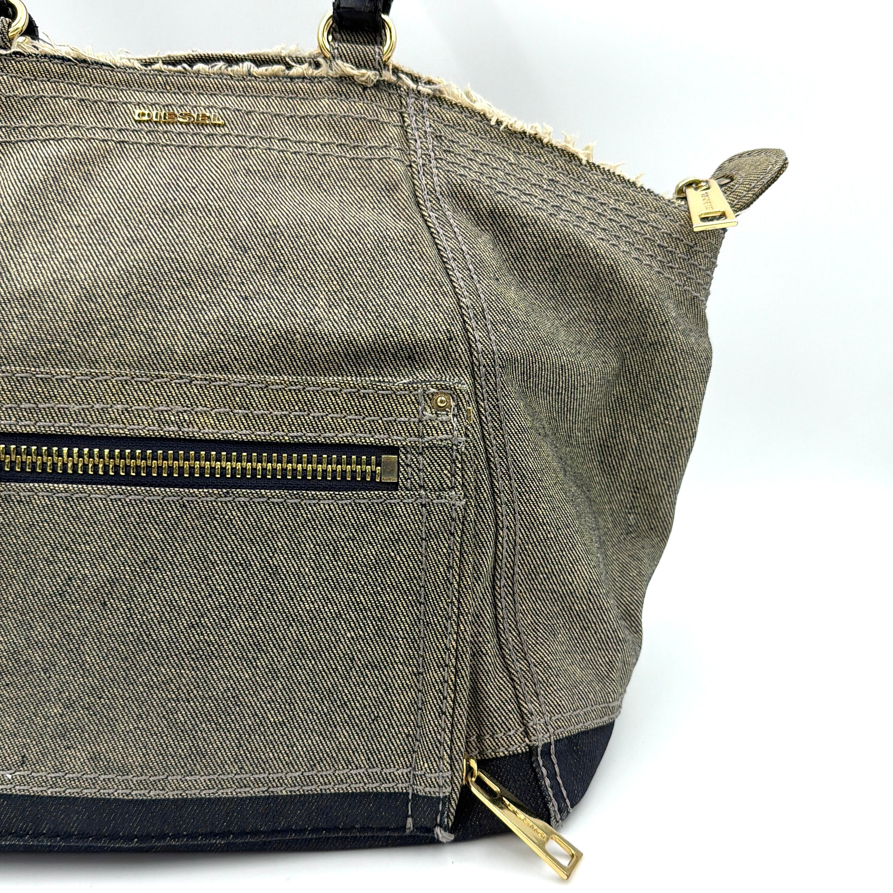 Diesel washed denim shoulder bag with black leather handles, gold zips and frayed edge detail.