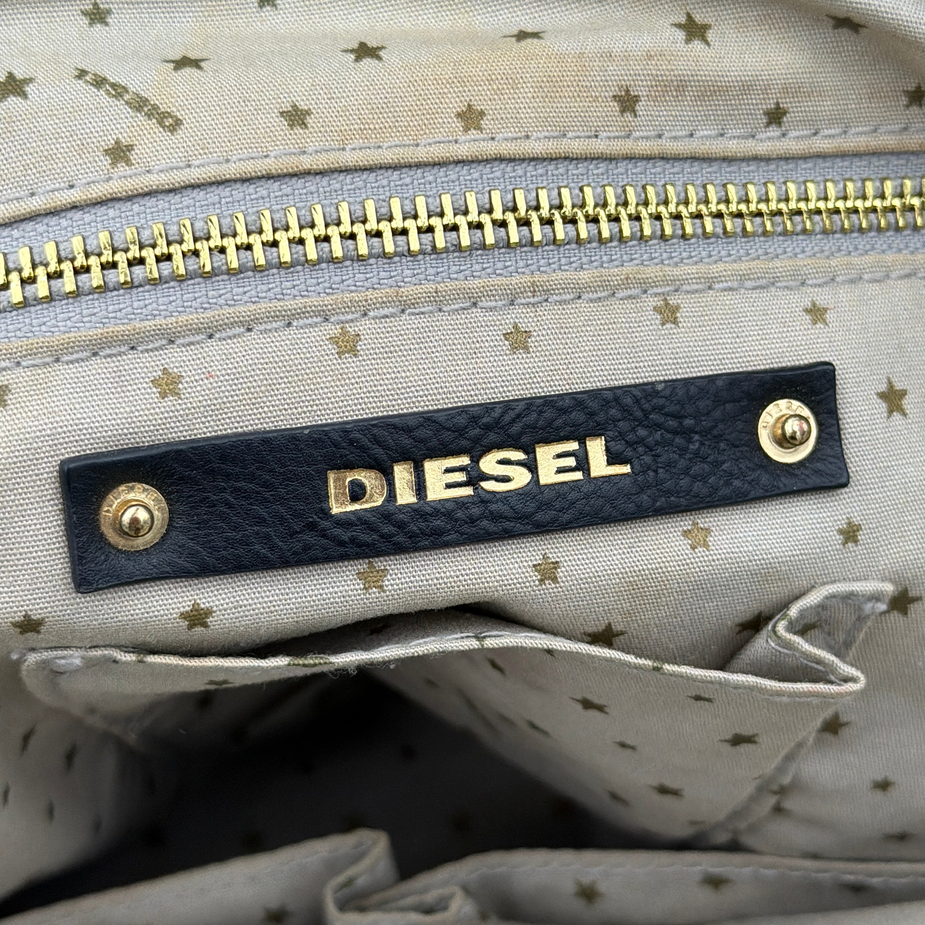 Diesel washed denim shoulder bag with black leather handles, gold zips and frayed edge detail.