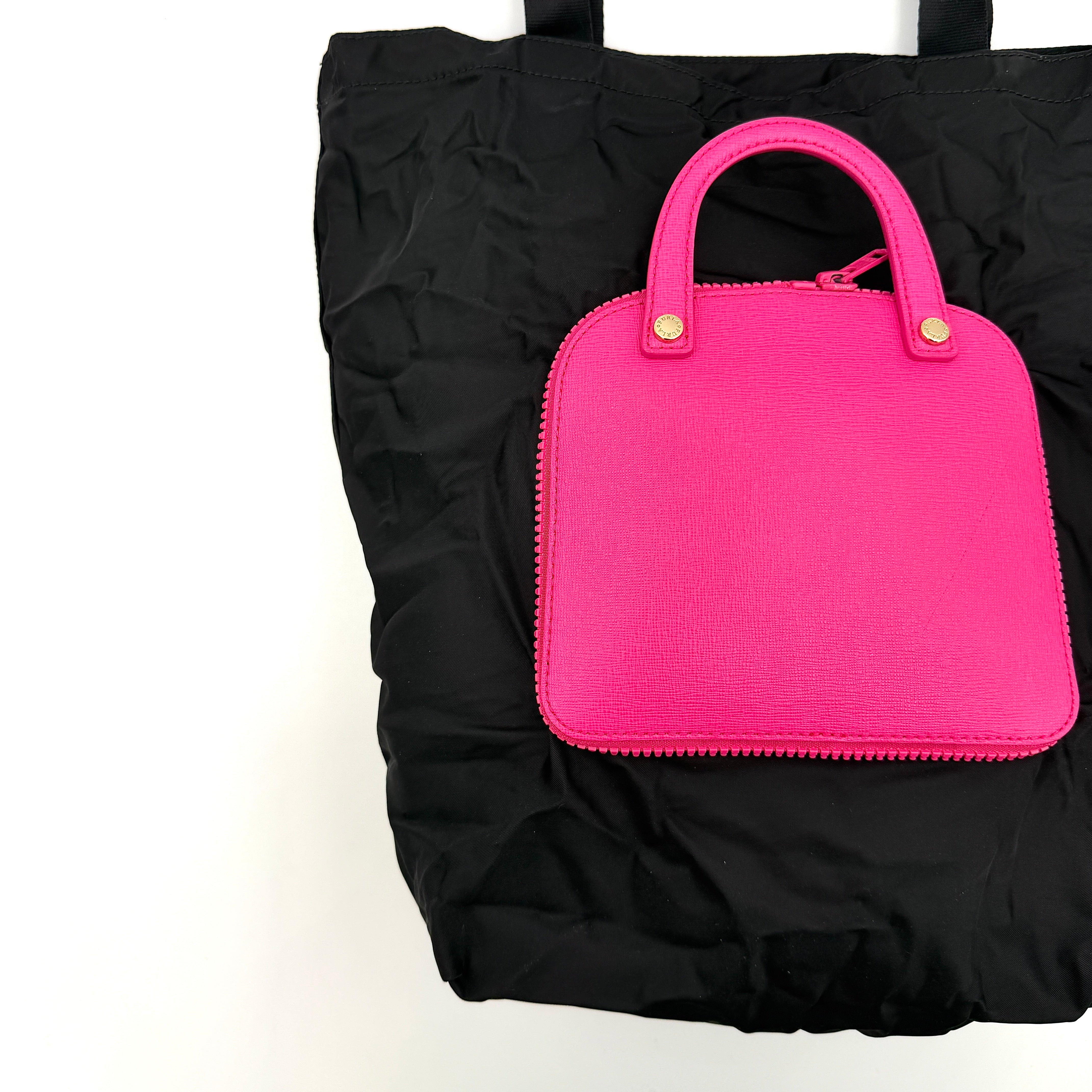 Furla black nylon tote bag with a bold pink zip pouch detail, styled as an exterior pocket, displayed flat to showcase its silhouette.