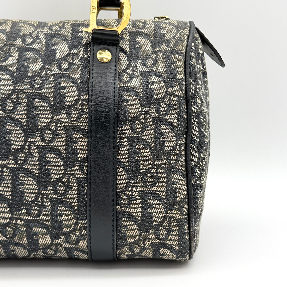 Christian Dior Trotter Monogram Boston Bag in grey and black canvas with gold hardware and black leather trim, shown upright against a white background.