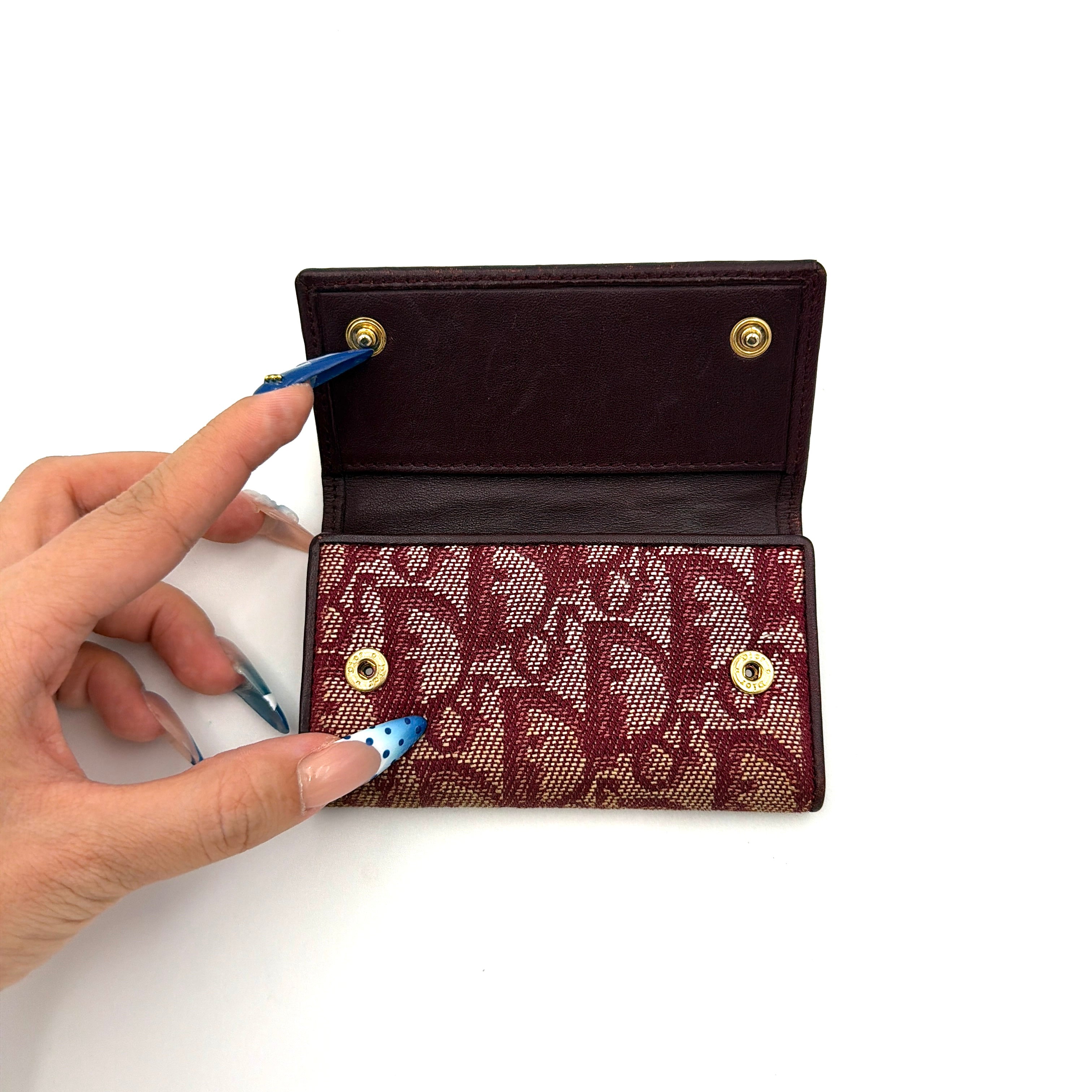 Dior Trotter Monogram key holder in red canvas with burgundy leather trim, photographed closed on a clean white background.