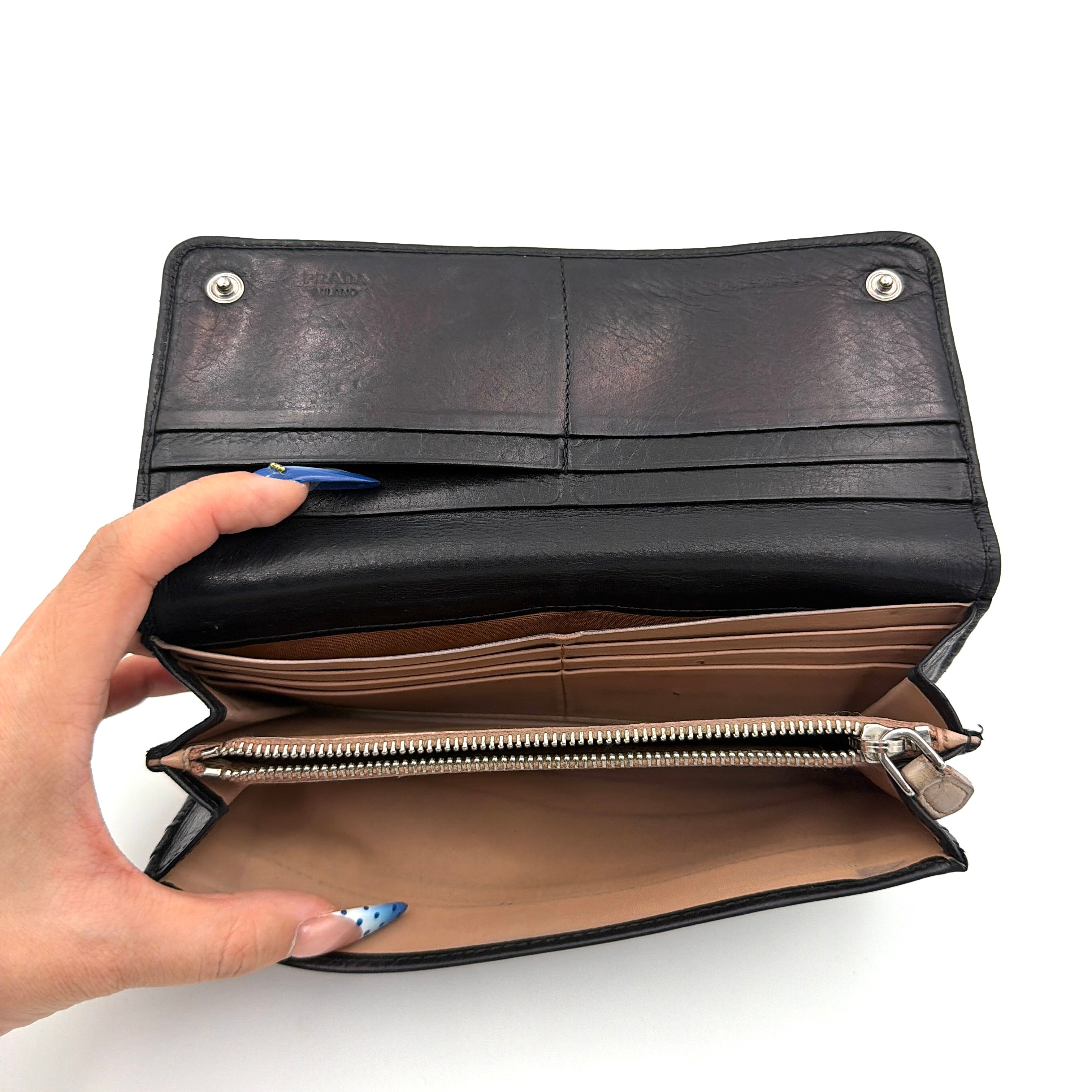 Prada Fiocco Bow Continental Wallet in black leather with a central grosgrain bow and silver-tone accents, displayed with refined simplicity.