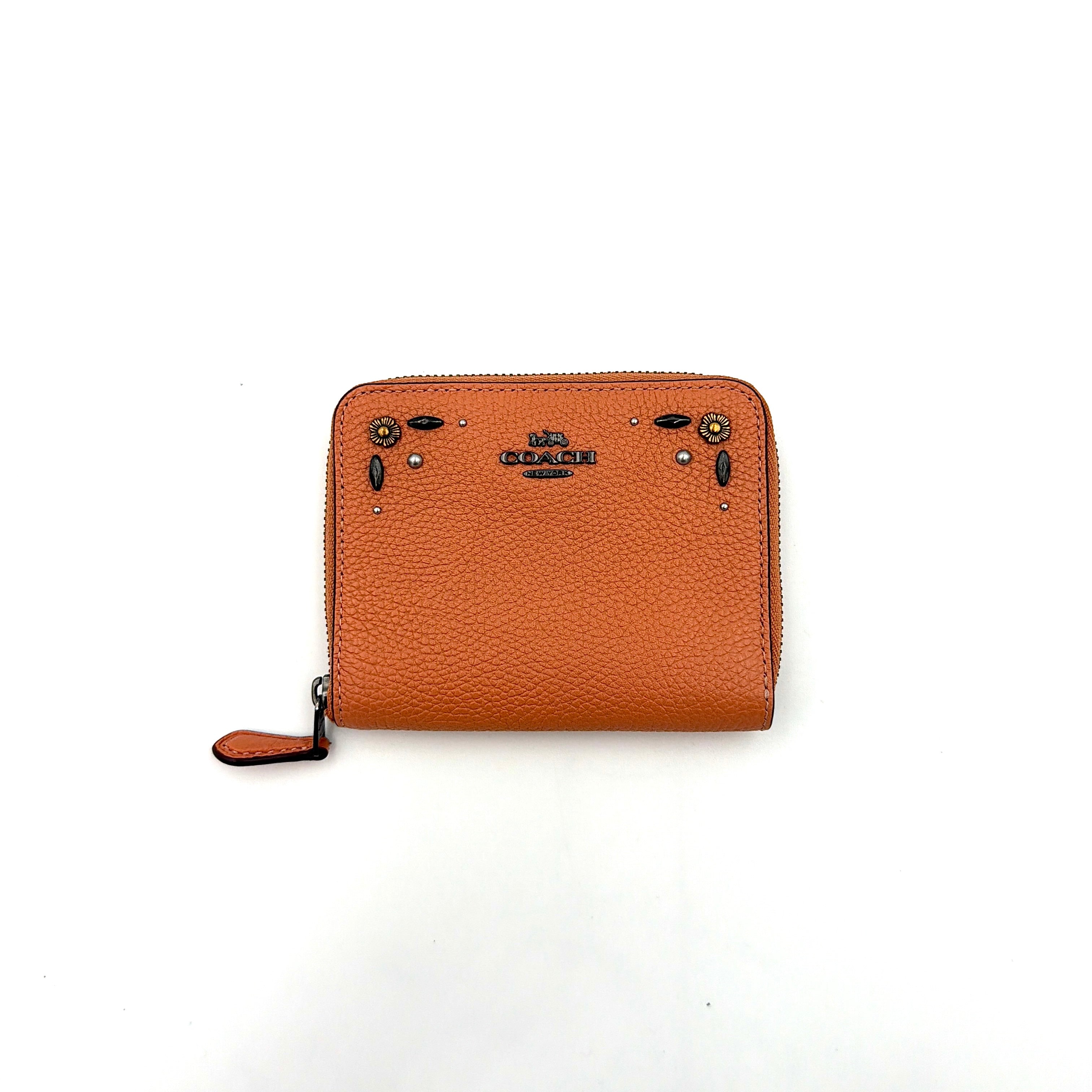 Coach Prairie Rivets Zip Around Small Wallet in orange pebbled leather with floral rivets and zip-around closure.