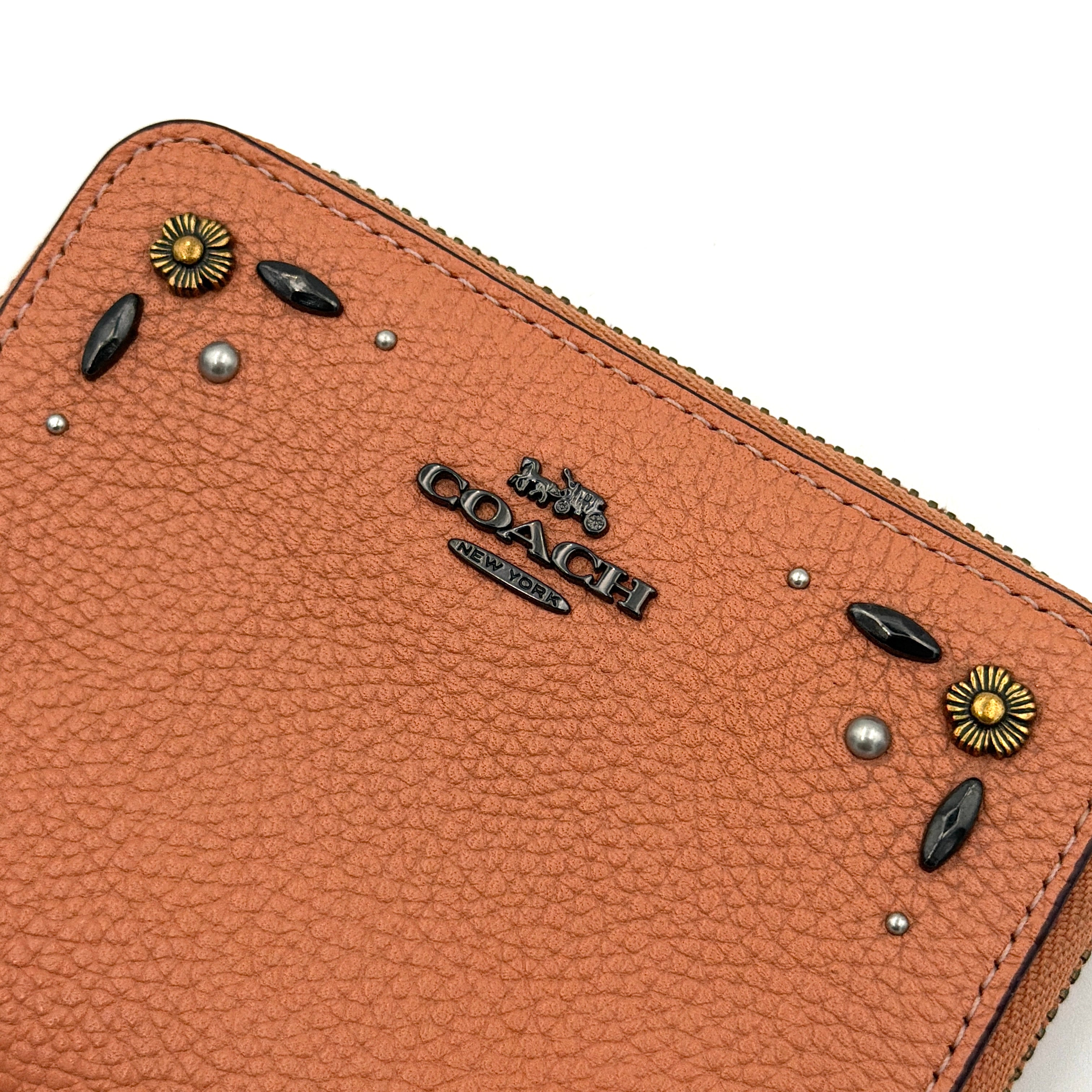 Coach Prairie Rivets Zip Around Small Wallet in orange pebbled leather with floral rivets and zip-around closure.
