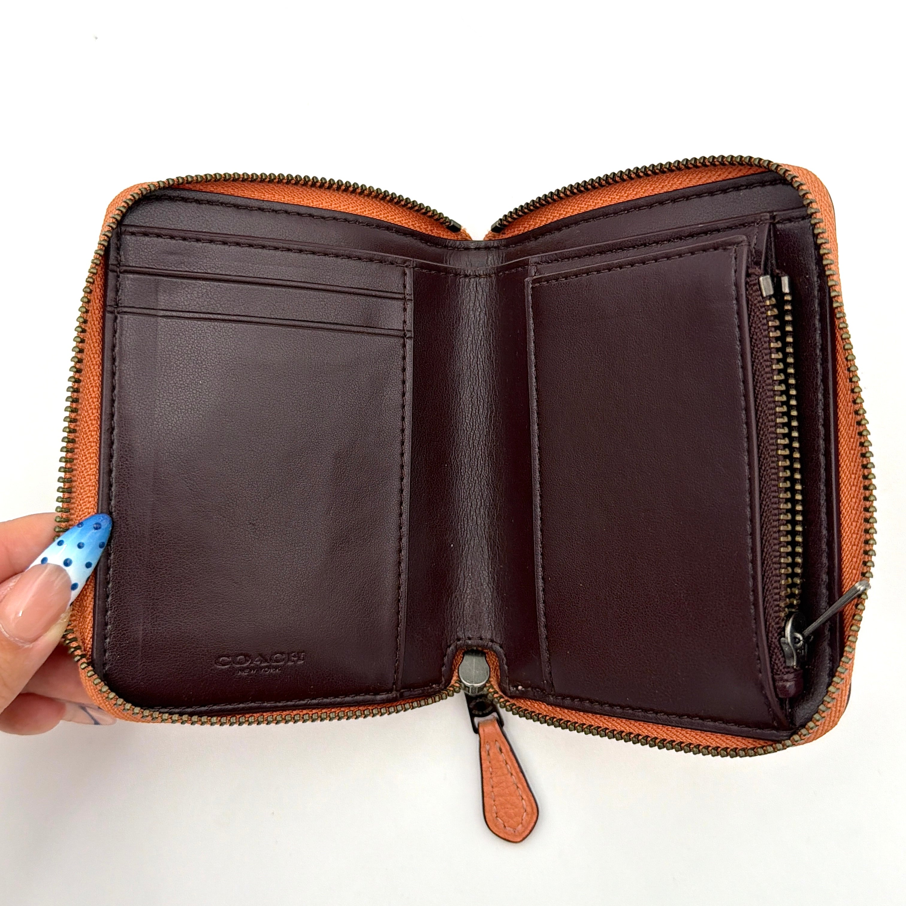 Coach Prairie Rivets Zip Around Small Wallet in orange pebbled leather with floral rivets and zip-around closure.