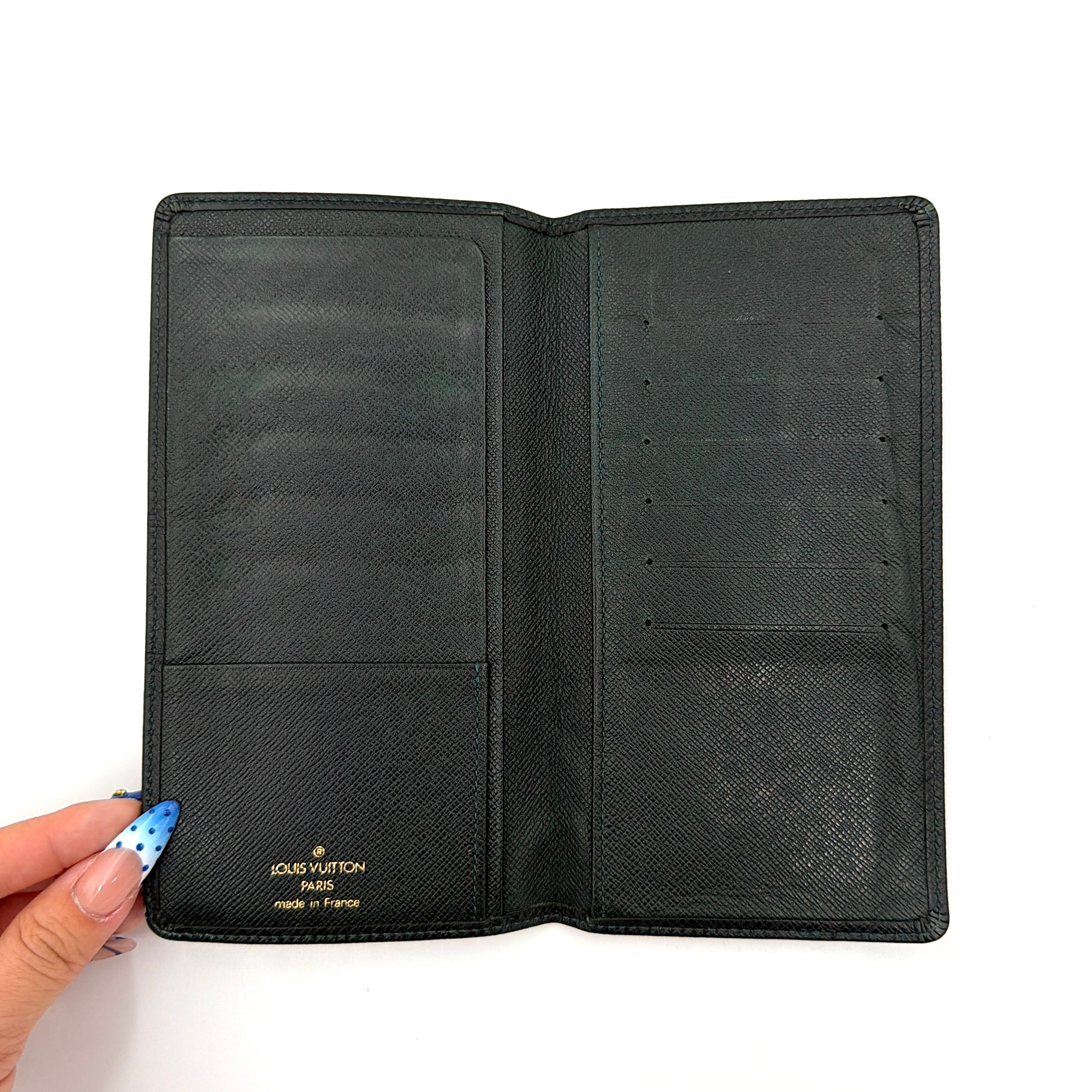 Louis Vuitton Taiga Brazza Wallet in dark green Taiga leather, showcasing a textured finish and iconic LV embossing in the bottom corner.