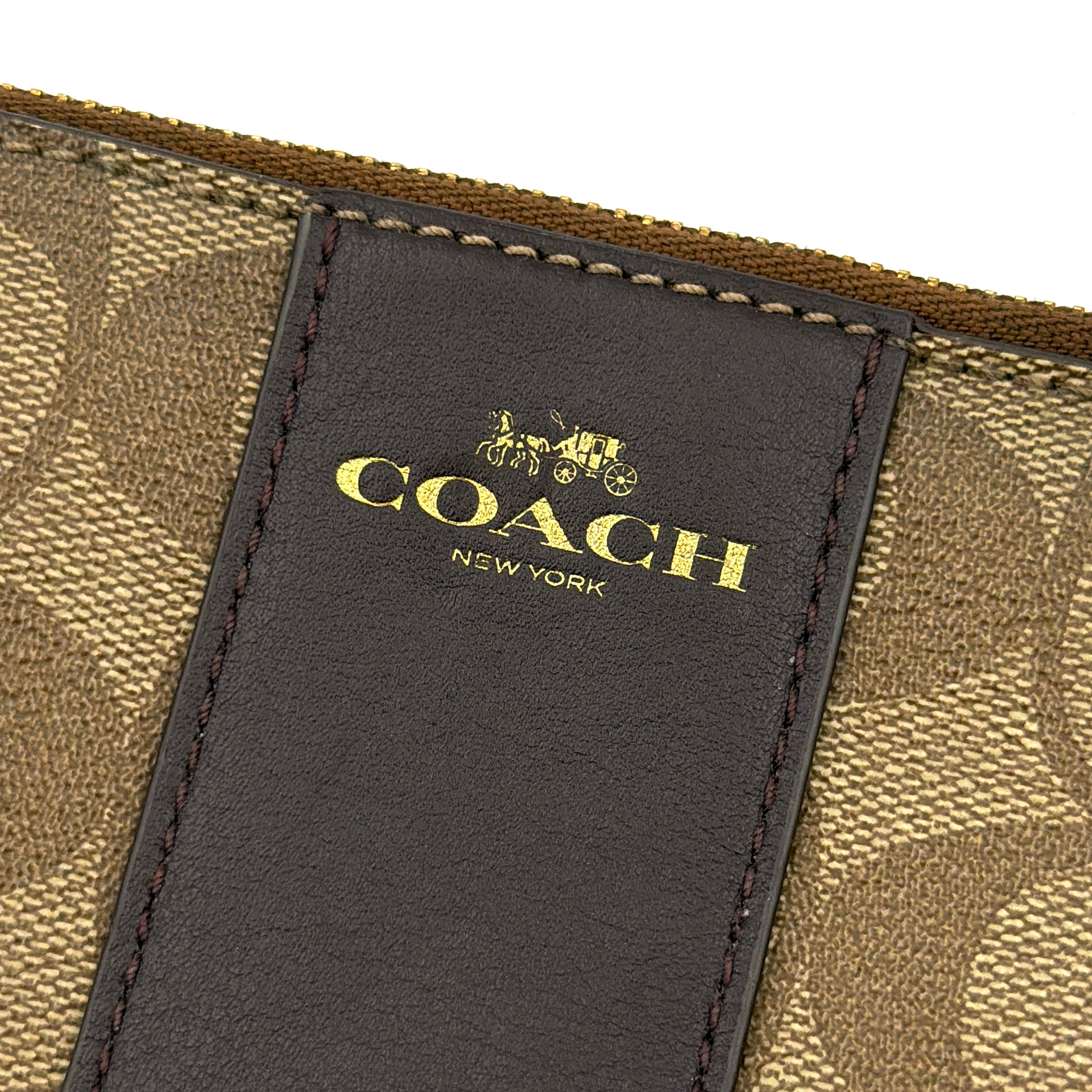 Coach Signature Stripe Corner Zip Wristlet in beige and brown canvas with a dark brown leather stripe and gold logo, shown with wristlet strap.